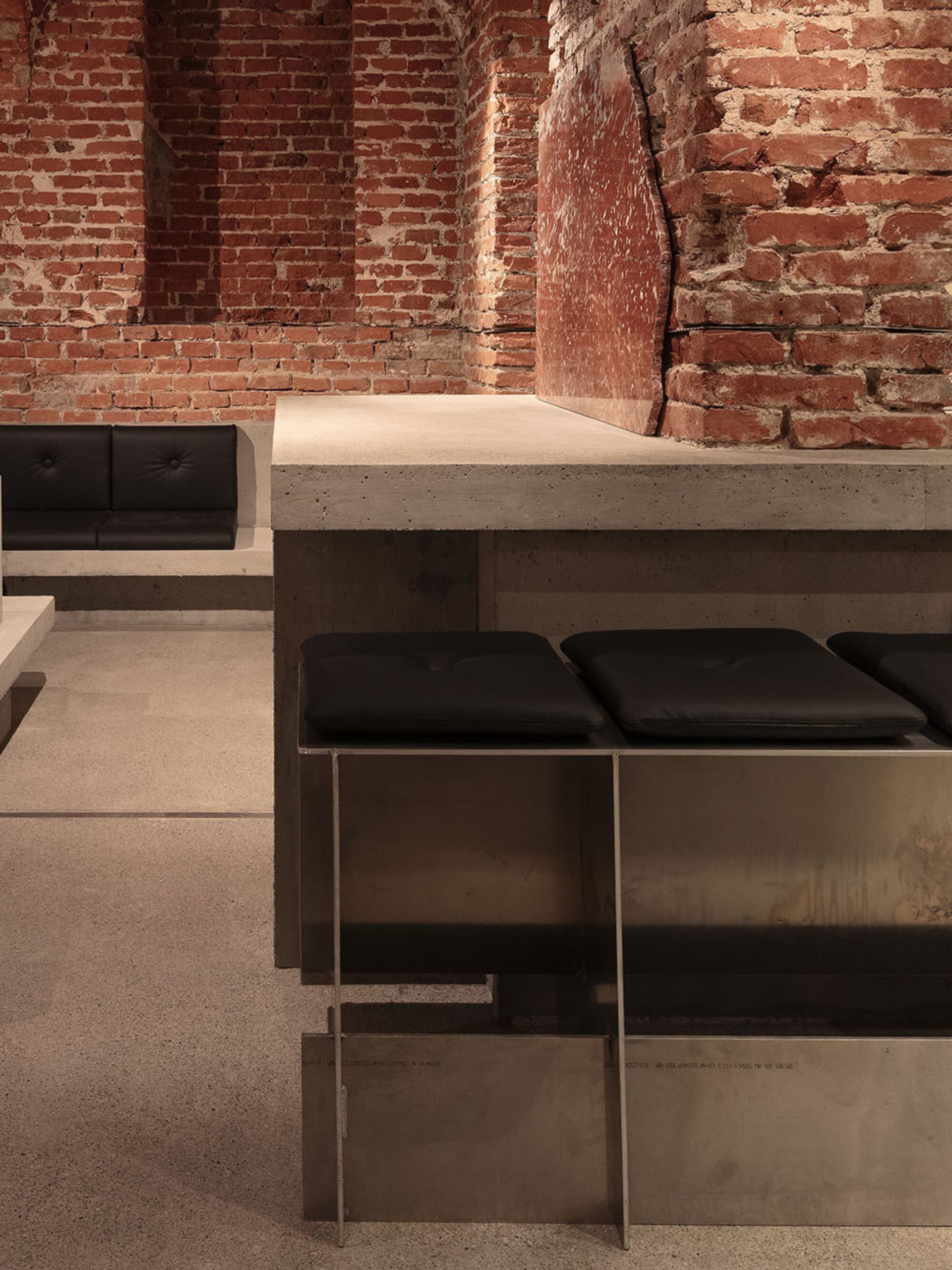 Cozy room with brick walls, two black stools, and two benches, creating a warm and inviting atmosphere