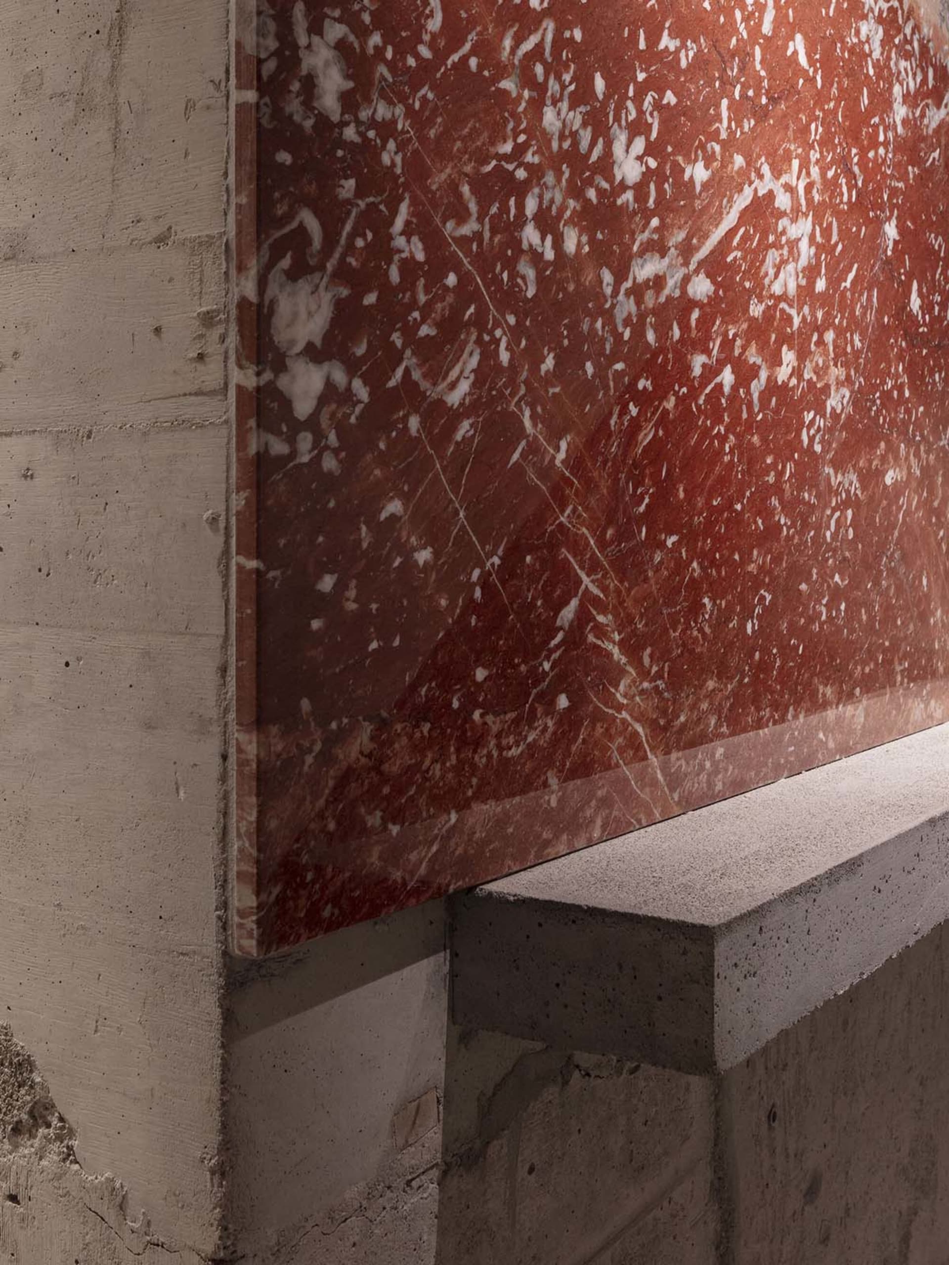 A modern staircase with a marble wall featuring a red tint, set against a clean and minimalistic background