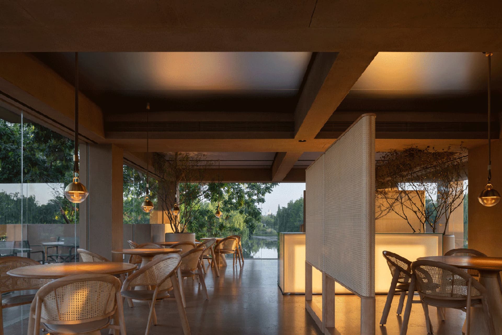 Cozy restaurant interior with wooden tables and chairs, potted plants, and a modern design