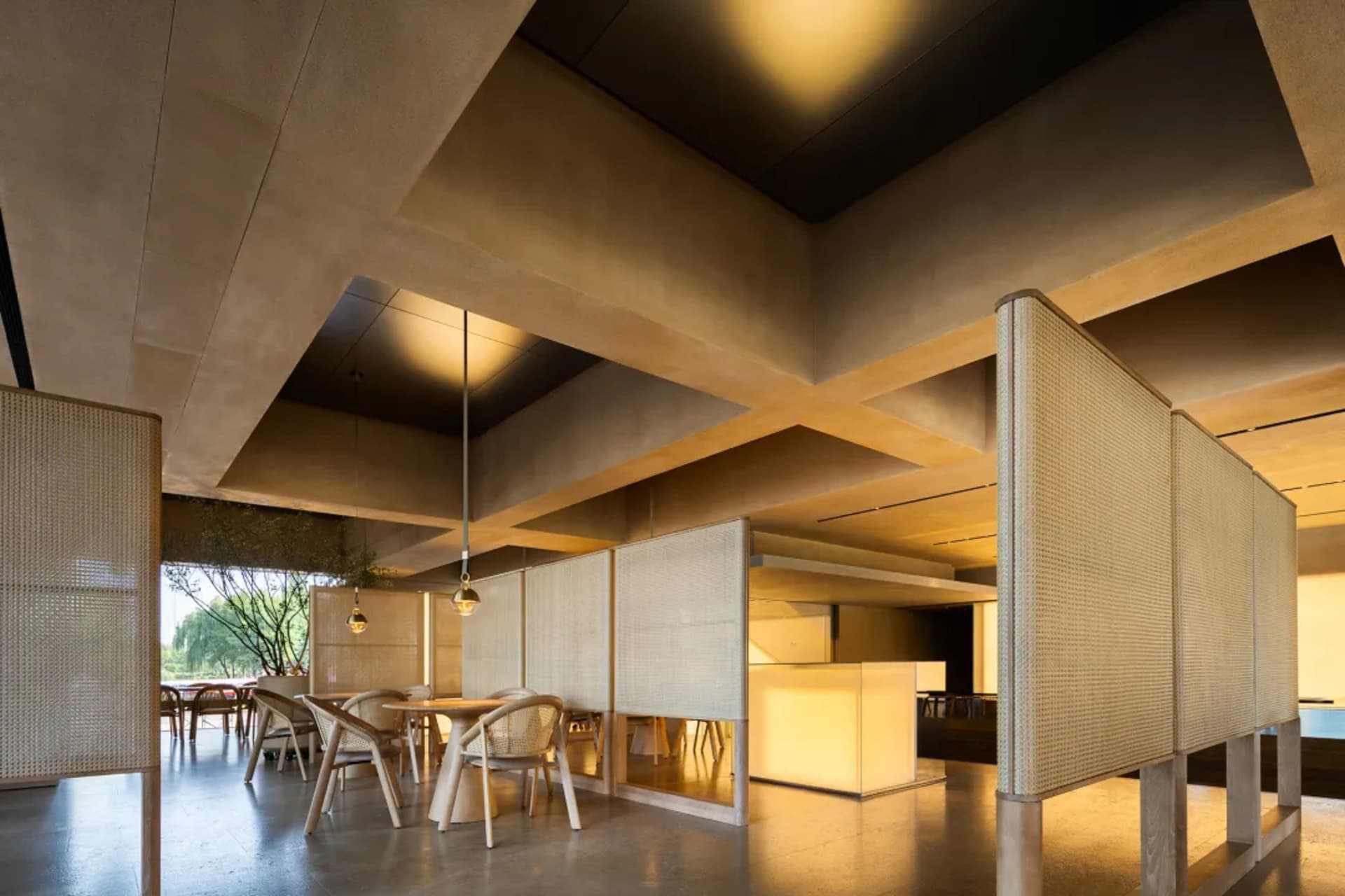 Modern restaurant interior with multiple dining tables, chairs, and natural light, featuring a combination of white and brown tones on the walls