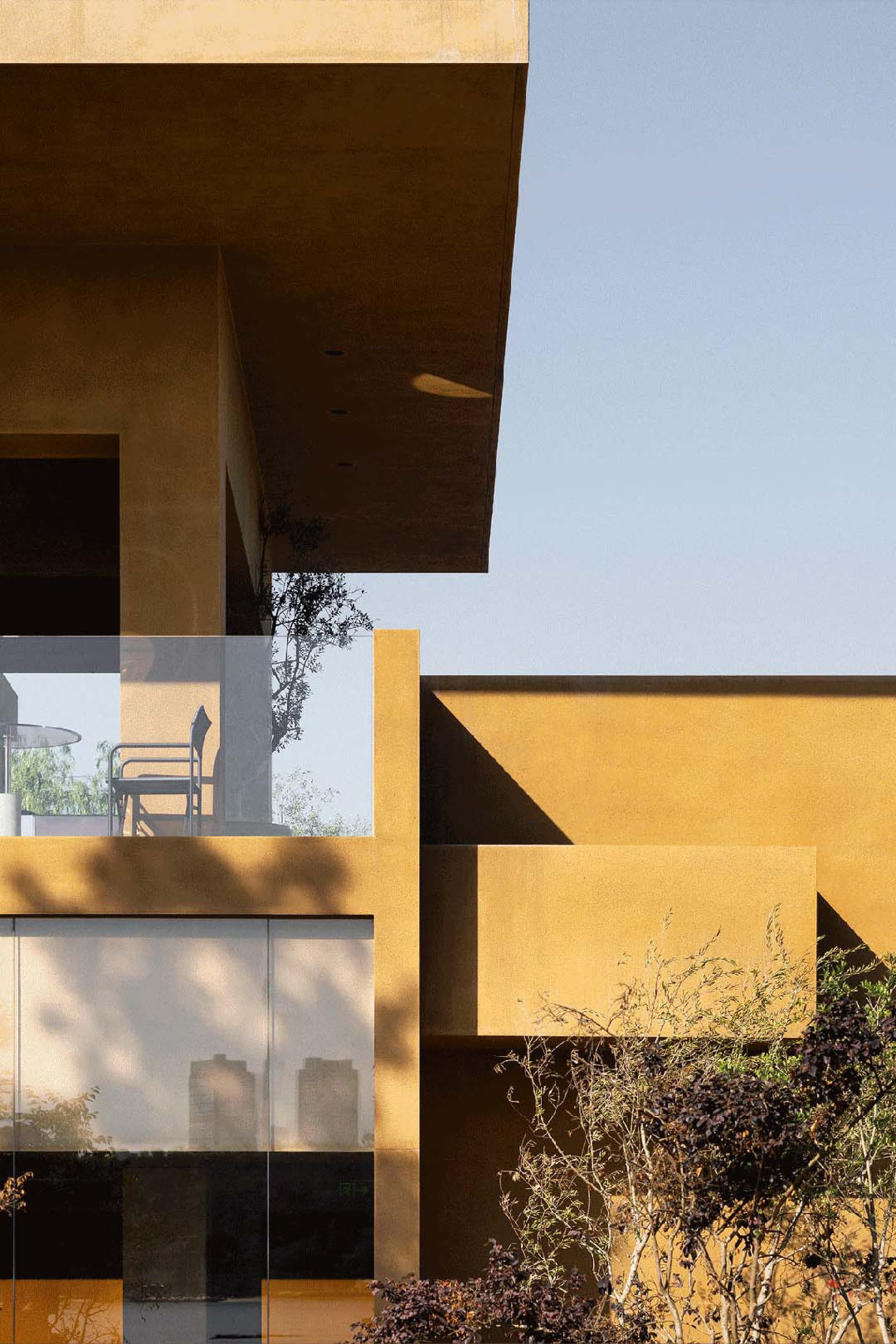 A residential house with a yellow exterior, a large window, and two chairs in front, showcasing a warm and inviting atmosphere