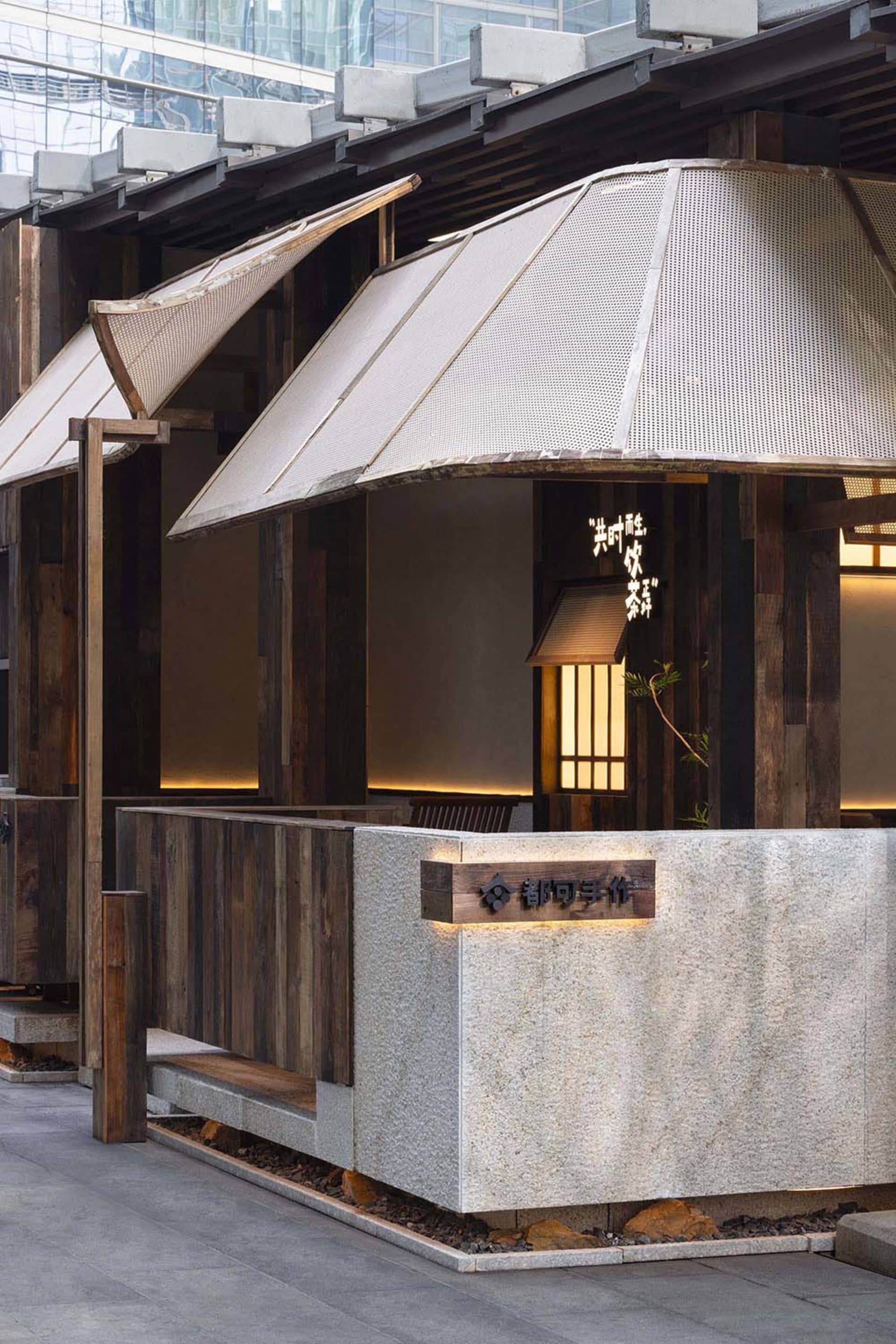 A warm and inviting Asian restaurant with wooden walls, stone countertops, and umbrella-like structures providing shade
