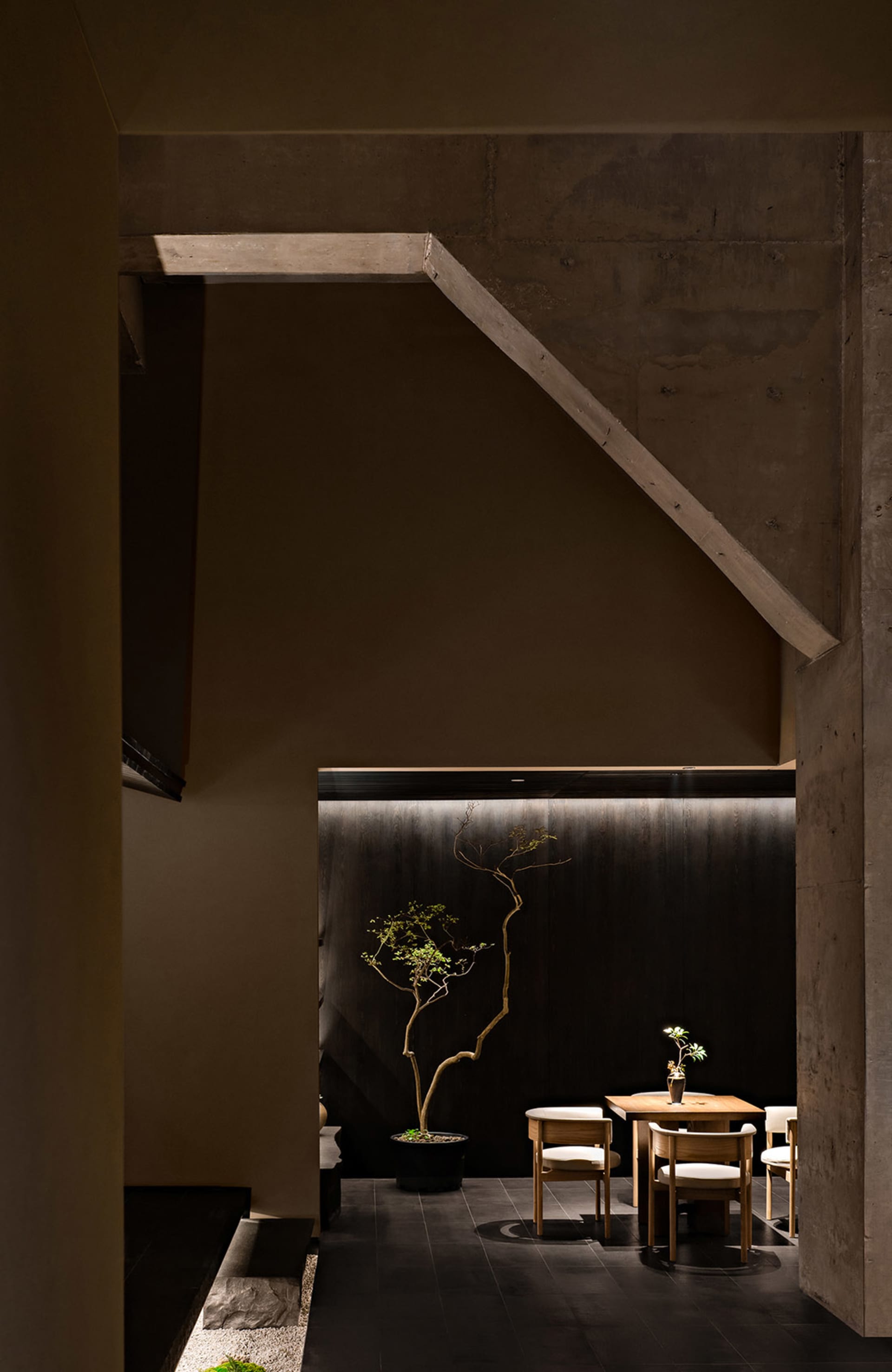 Cozy cafe interior with a wooden table, chairs, potted plants, and a vase, featuring a warm and inviting atmosphere with brown and white tones
