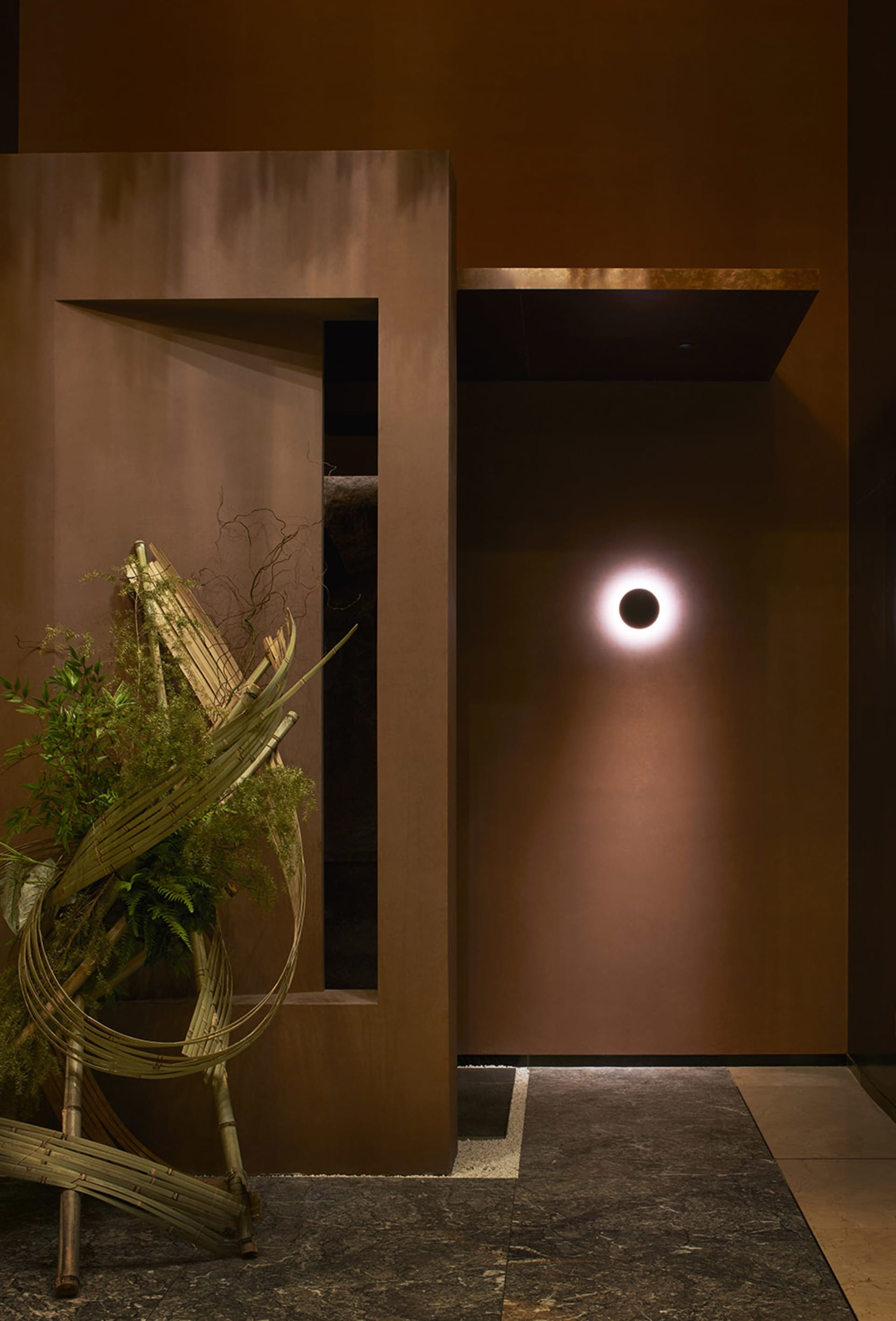 Warm and inviting interior space with a brown wall, potted plants, and a vase, featuring earthy tones and natural elements