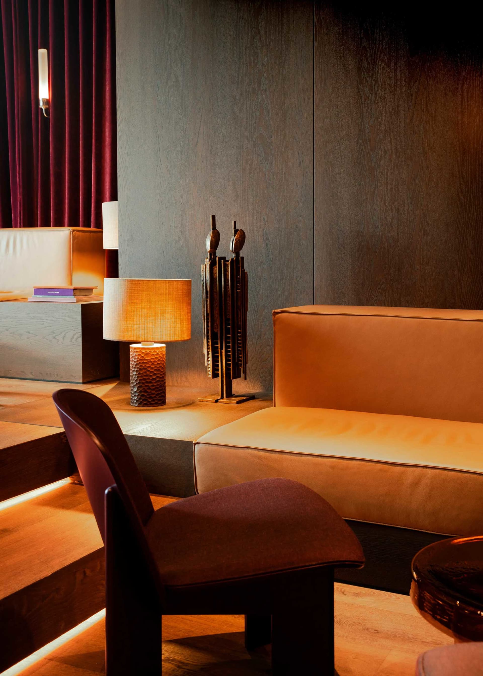 Cozy living space with two couches, two chairs, and three lamps, featuring wooden and leather furniture in a warm and inviting atmosphere