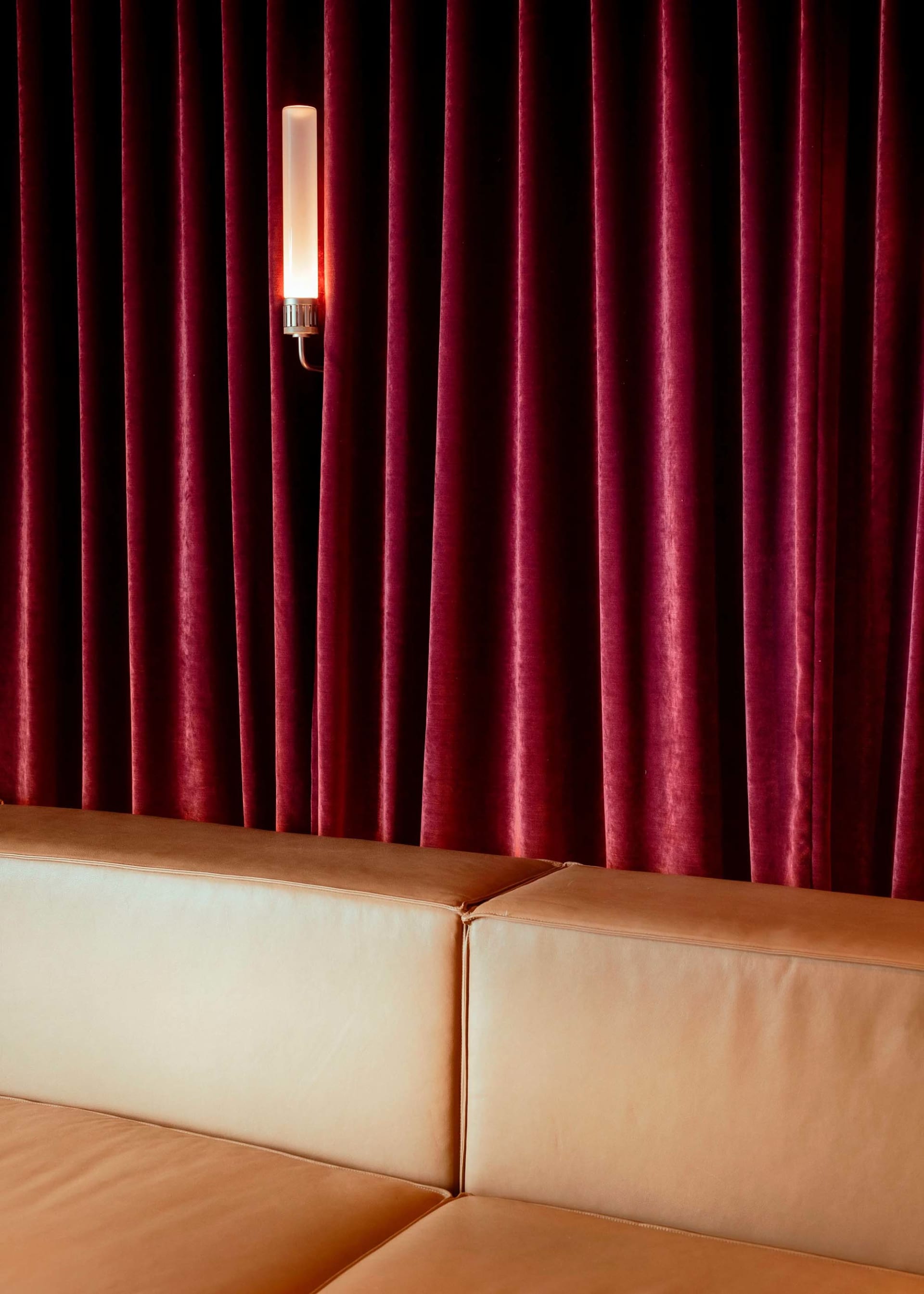 Cozy living room with two couches, chairs, and a red velvet curtain wall, creating a warm and inviting atmosphere