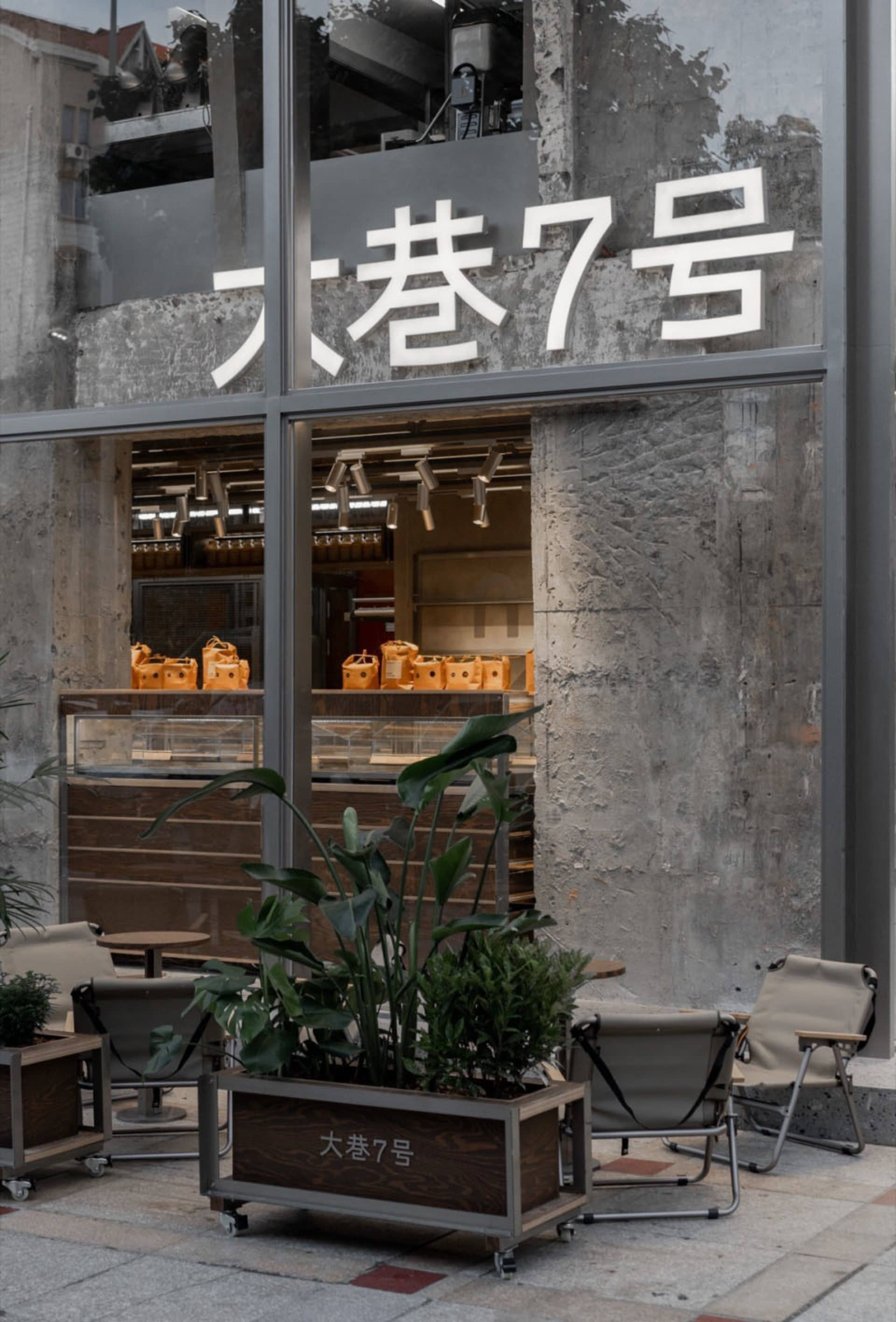A modern retail storefront with a large window display of handbags, surrounded by chairs for customer seating and a stylish atmosphere