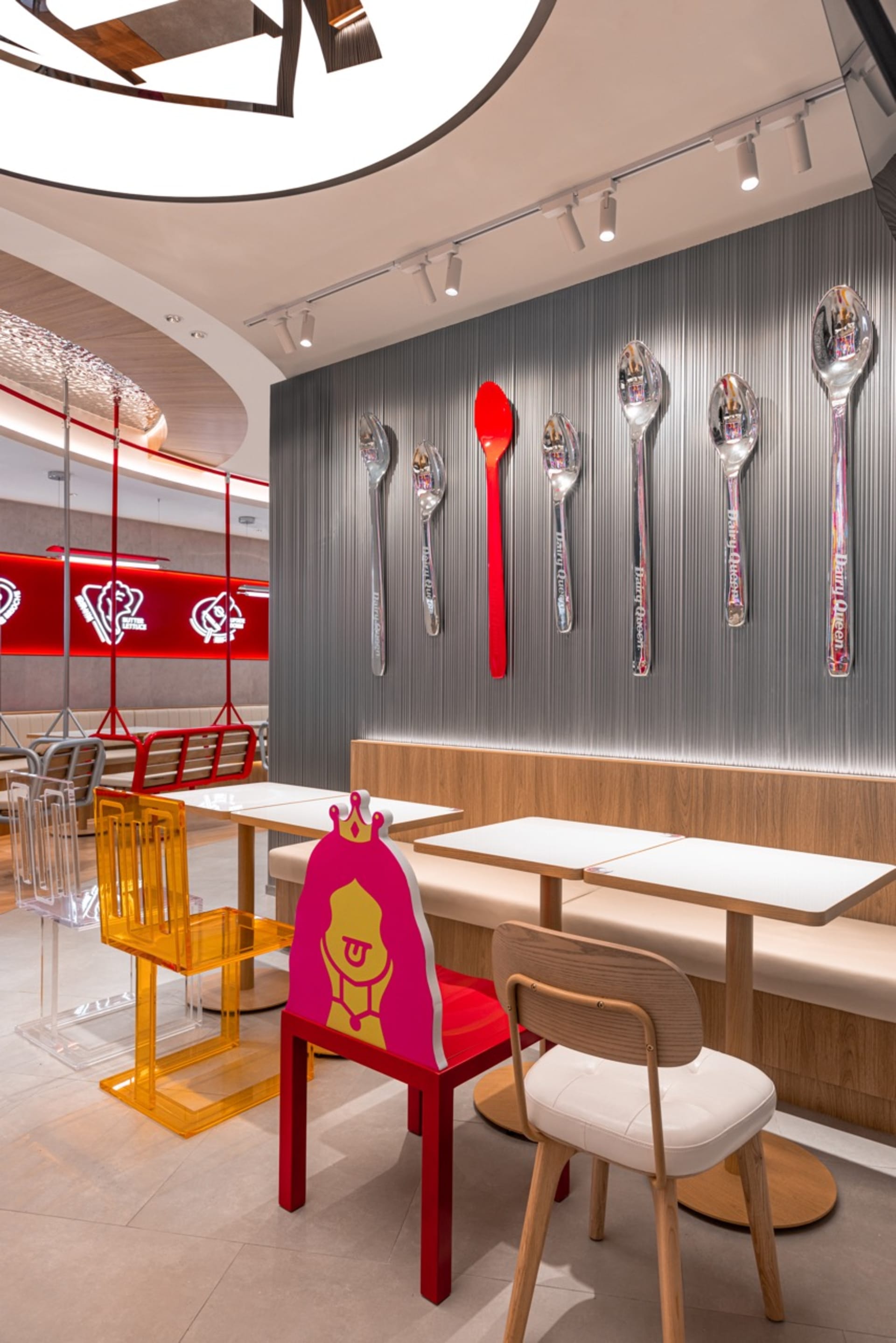 現代餐廳用餐區，設有白色桌布、椅子，以及牆上懸掛的裝飾湯匙，營造乾淨且溫馨的氛圍