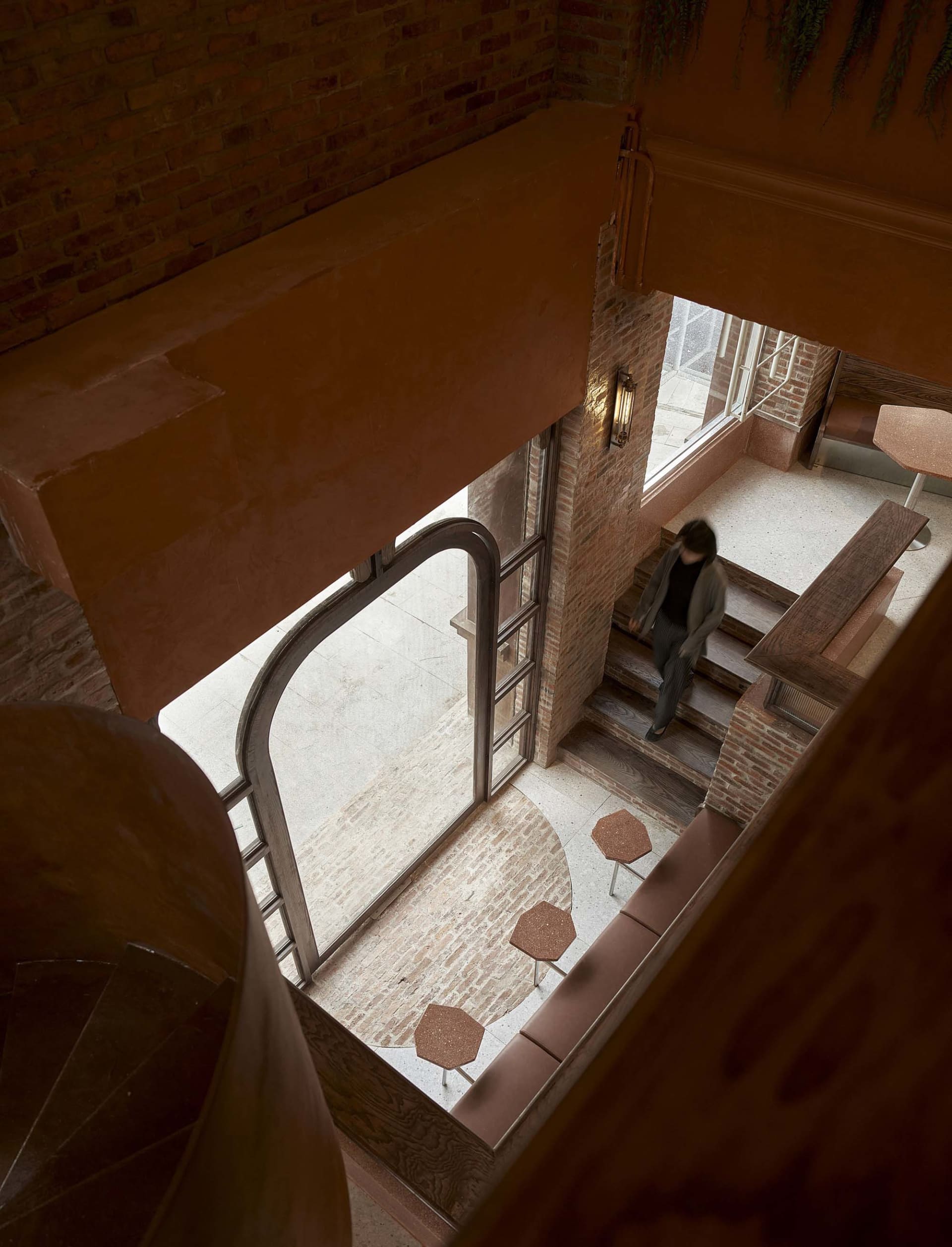 Cozy interior space with a brick building, a staircase, a dining table, chairs, and benches, with a warm and inviting atmosphere