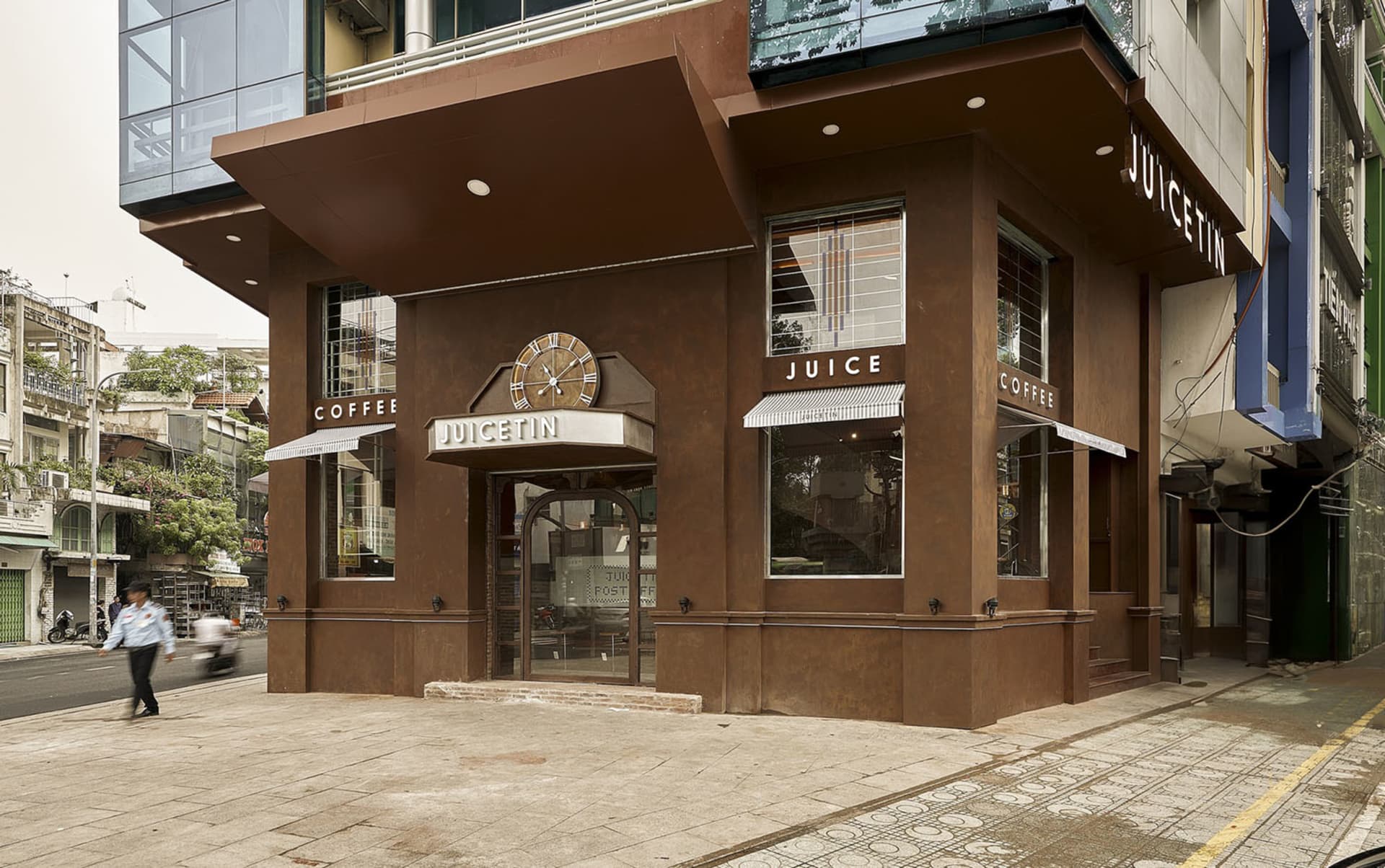 Exterior view of a cozy coffee shop with a brown building, a clock, a fireplace, and seating areas