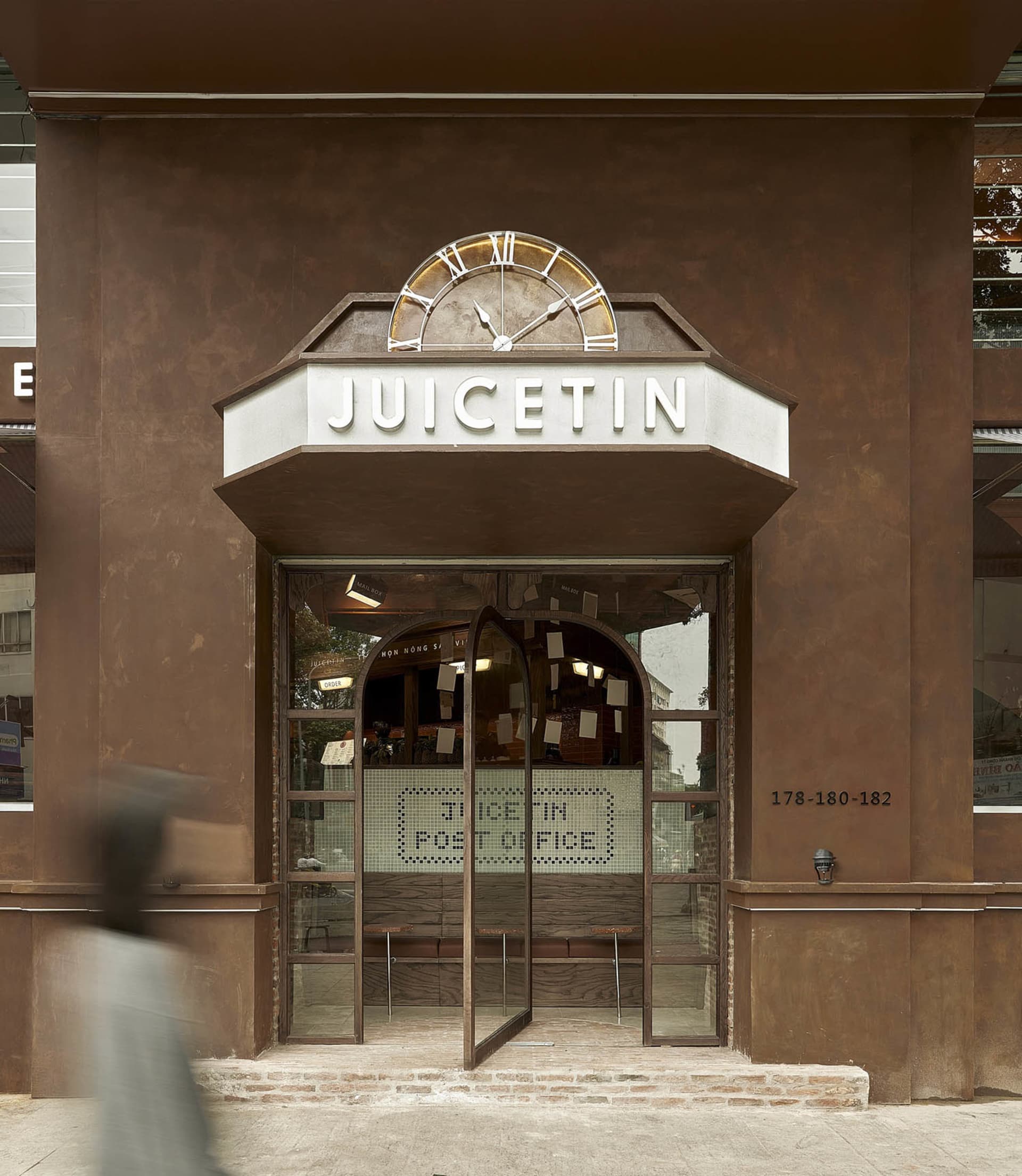 A spacious cafe interior with a large Roman numeral clock on the wall, surrounded by dining chairs and tables in a welcoming atmosphere
