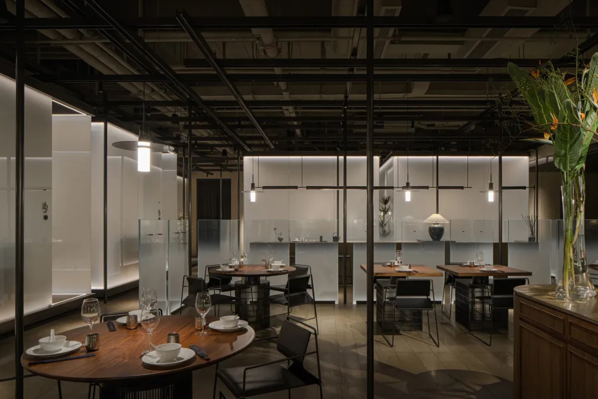 Quiet restaurant interior at night with wood flooring, wine glasses on tables, and elegant design elements