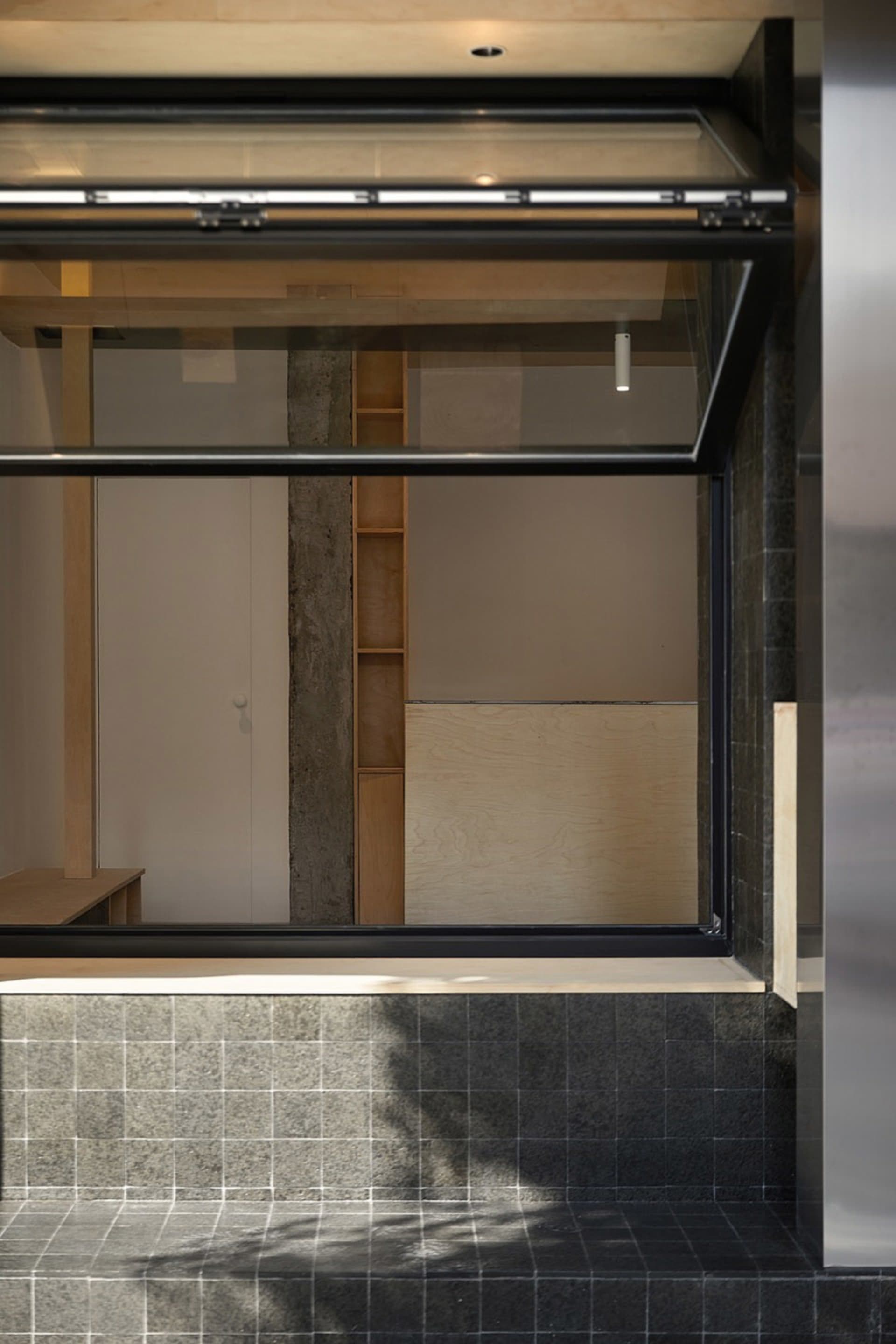 Empty modern living space with a large window, tiled walls, cabinets, and countertops, flooded with sunlight