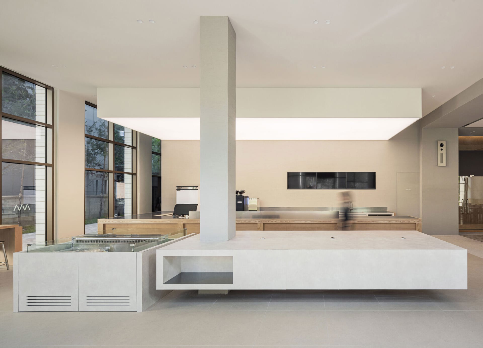 Open kitchen with a large island featuring a sink and refrigerator, two ovens, and white cabinets and walls