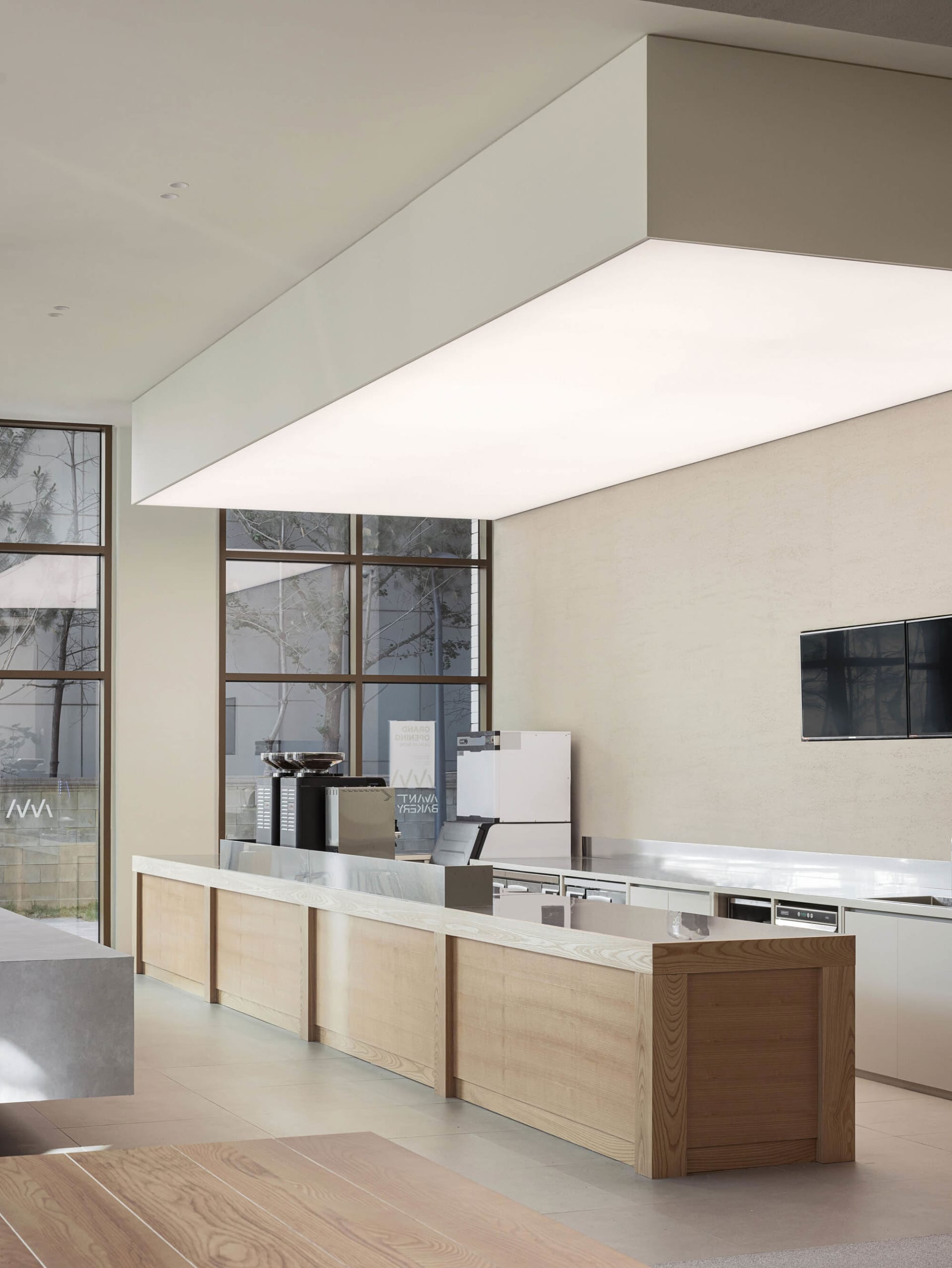 Open kitchen with a large island, two sinks, and various appliances, surrounded by wooden walls and filled with natural light