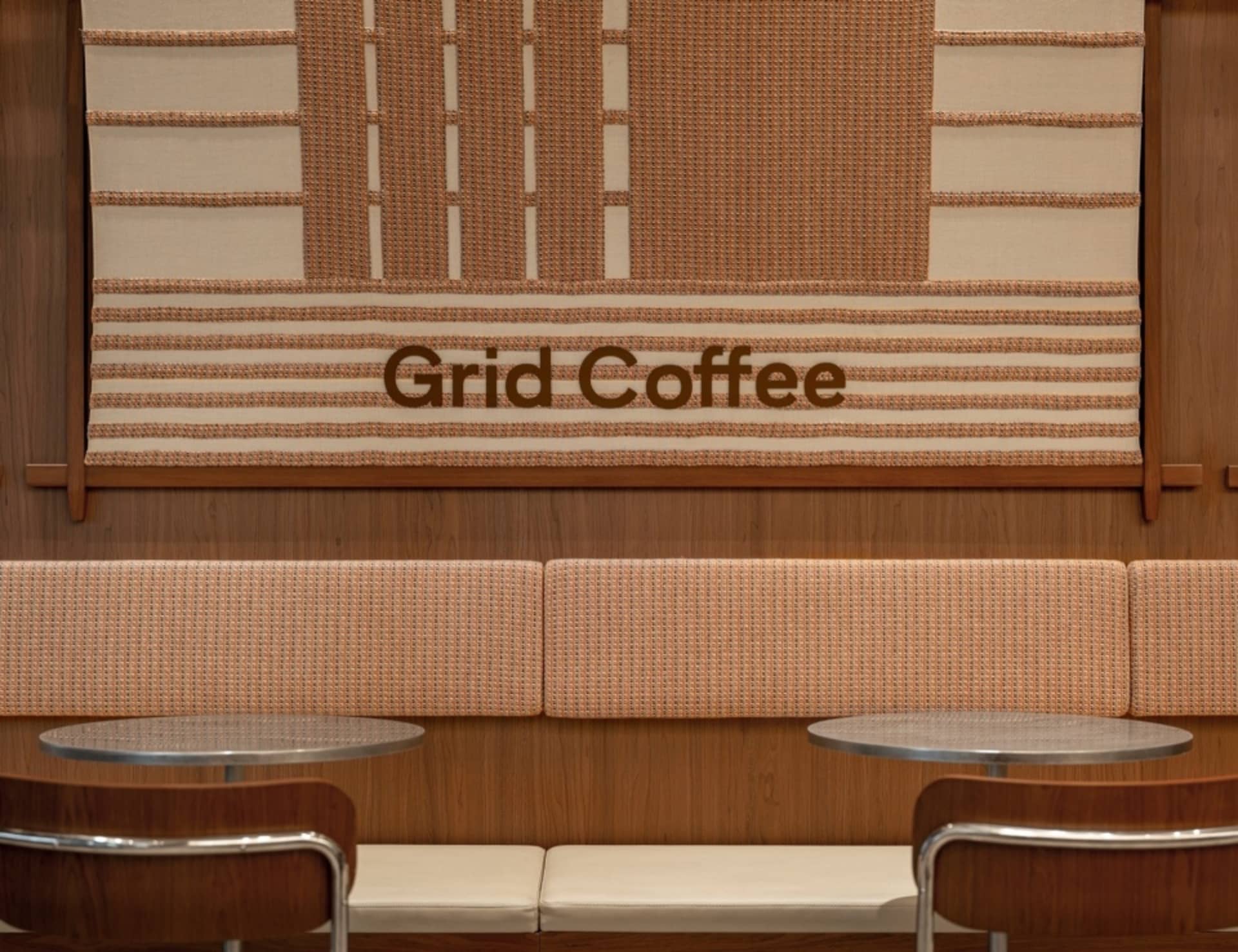 溫馨座位區，兩張沙發與兩張餐桌置於「Grid Coffee」格柵牆前，氛圍誘人