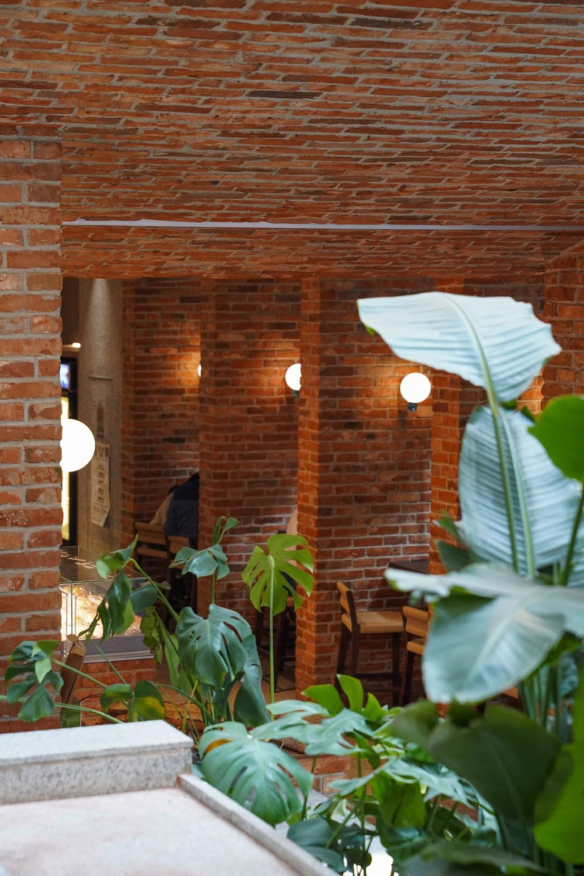 Warm and inviting restaurant space with brick walls, potted plants, and seating areas