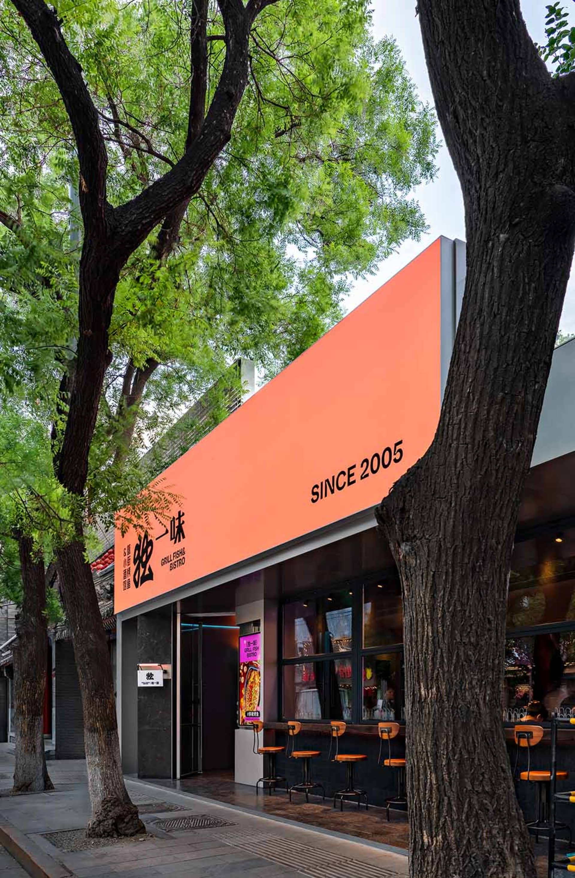 A colorful restaurant with an orange building, outdoor seating, and a large sign