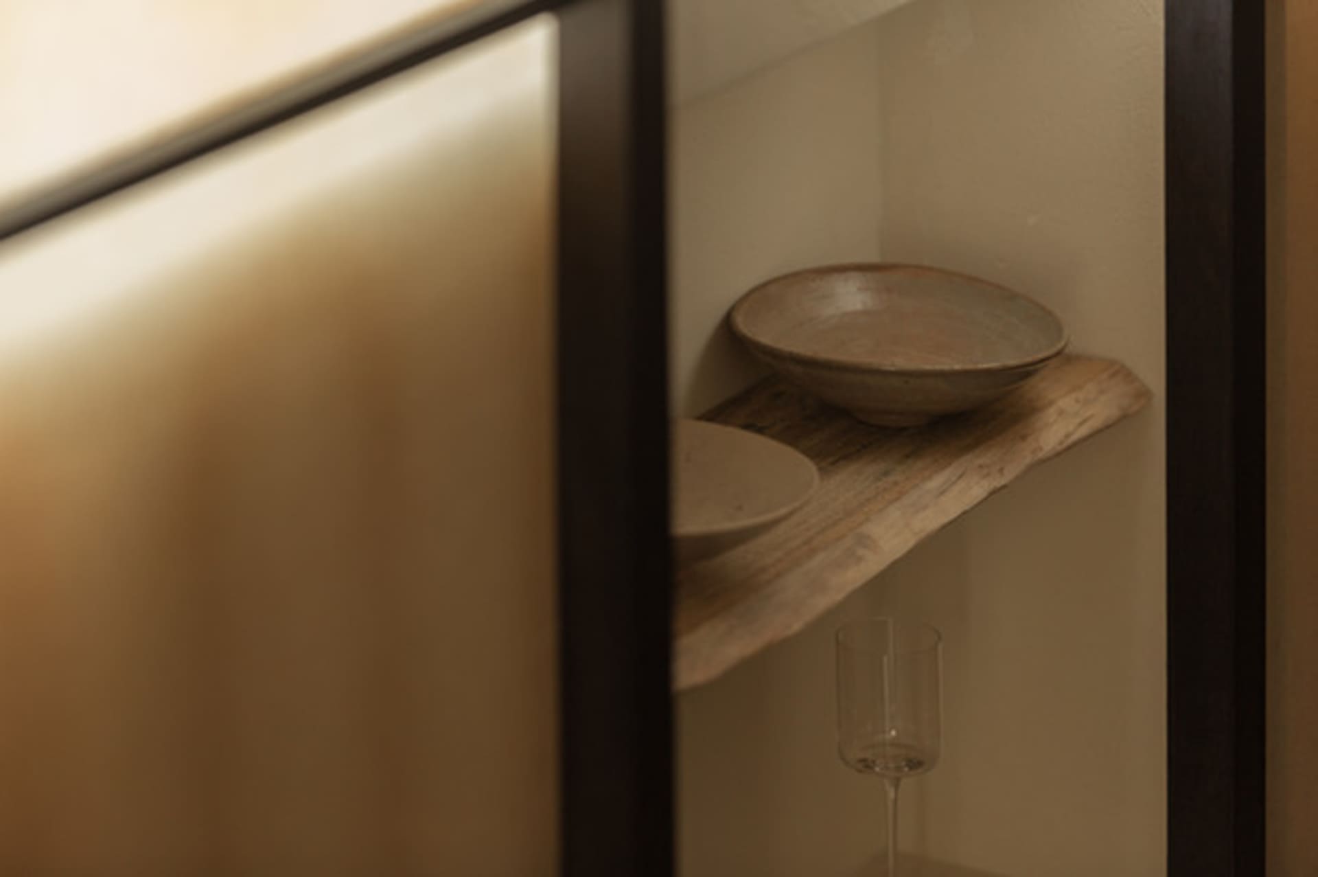 A wooden shelf in a bathroom holds three bowls of varying sizes, creating a functional storage solution with a warm and rustic feel