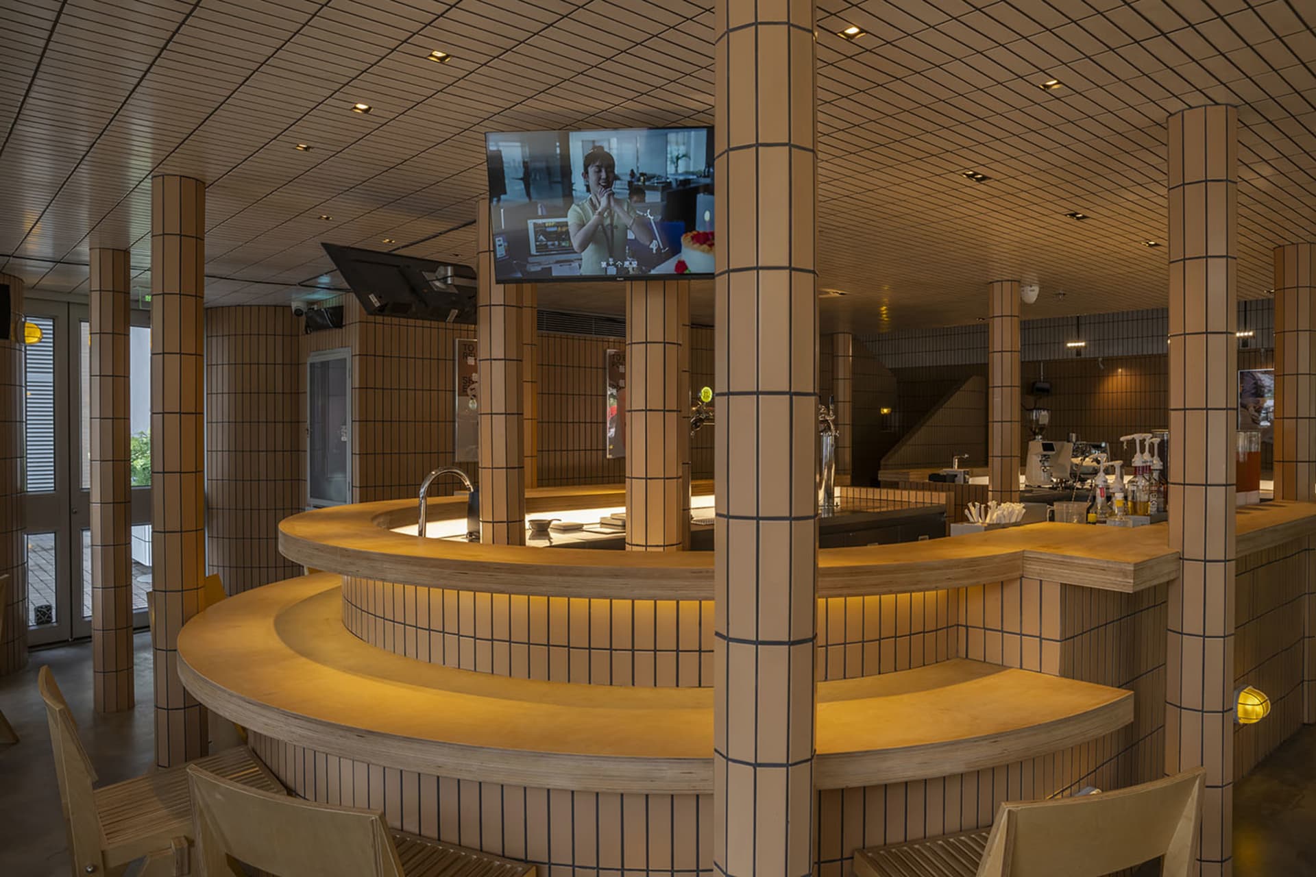 Modern restaurant bar with a TV mounted above it, featuring two chairs and a comfortable atmosphere