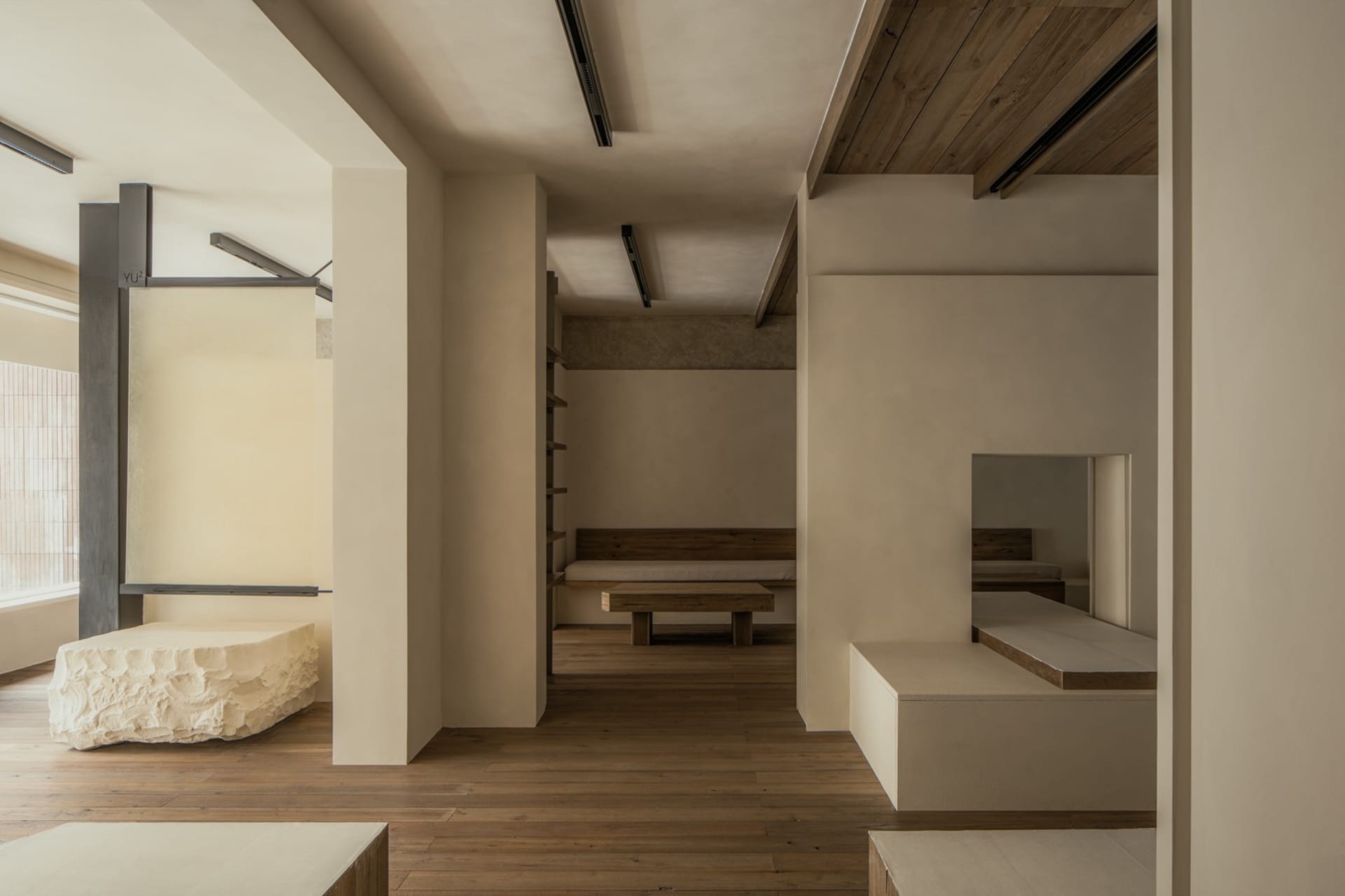 A calm and inviting empty room with wooden floors and white walls, featuring two benches and a large open area