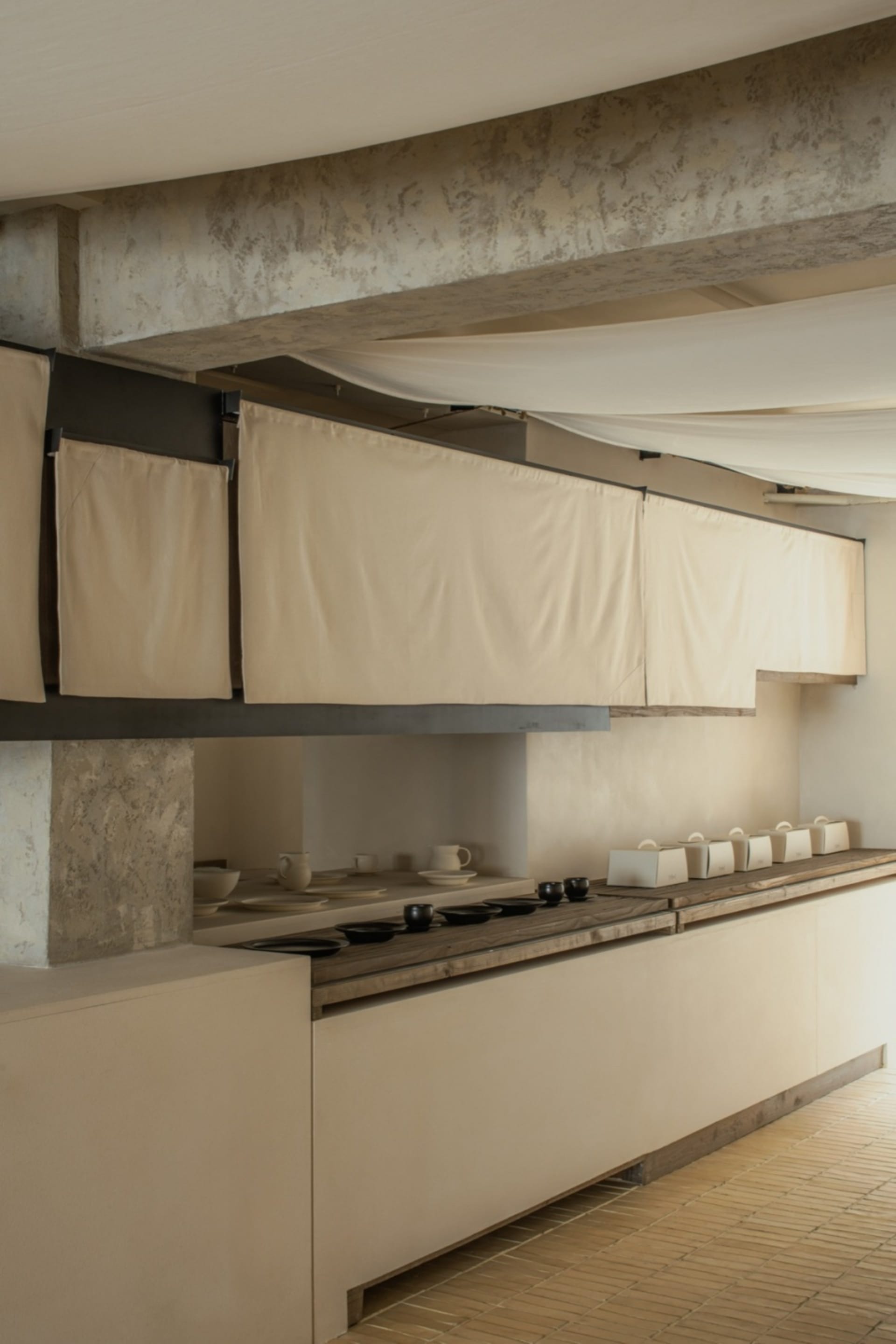 Empty kitchen with white walls and cabinets, featuring bowls, cups, and vases on countertops in a clean and minimalistic atmosphere