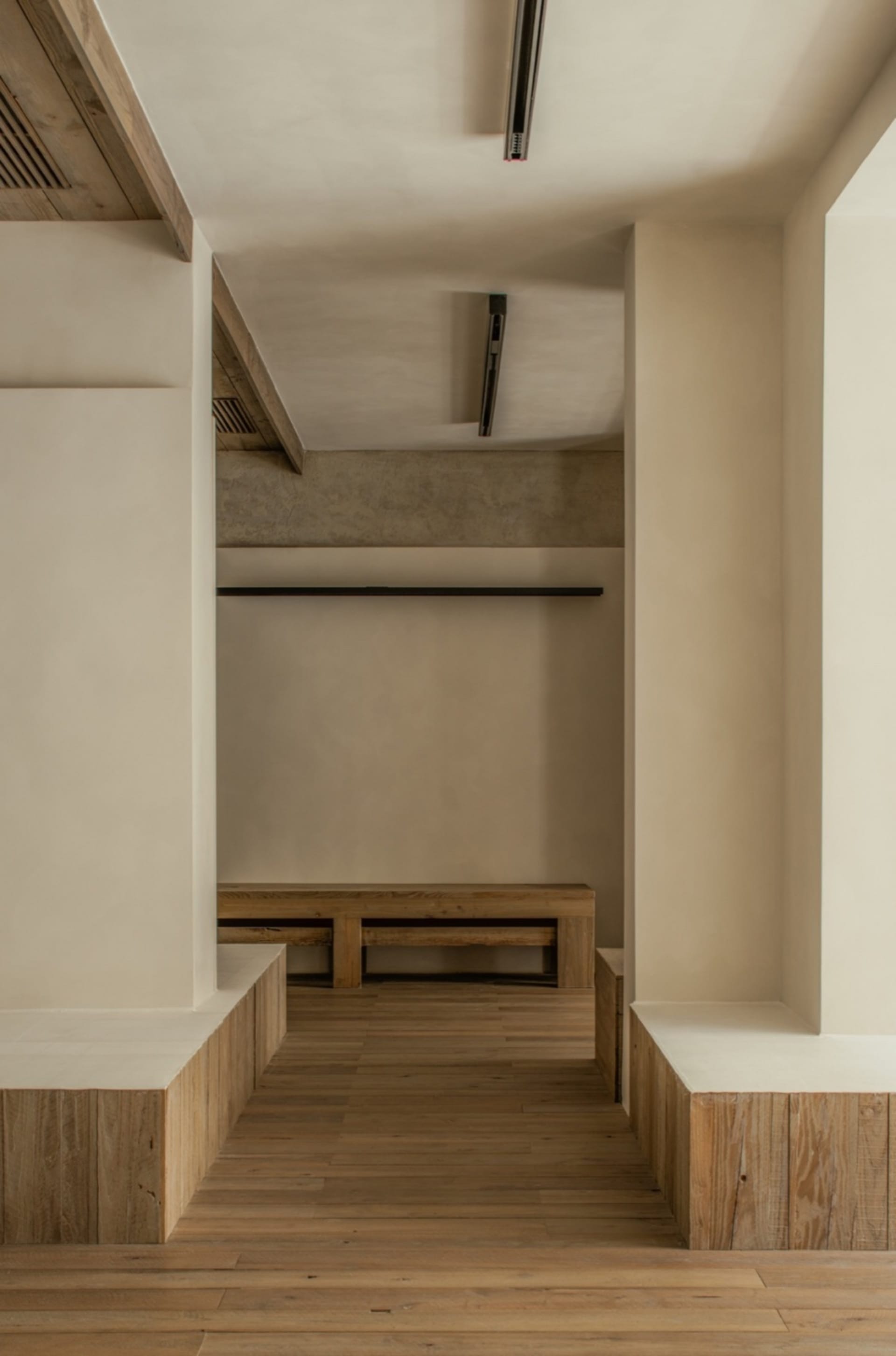 Empty lobby with wooden floors and walls, featuring two benches and a calm, inviting atmosphere