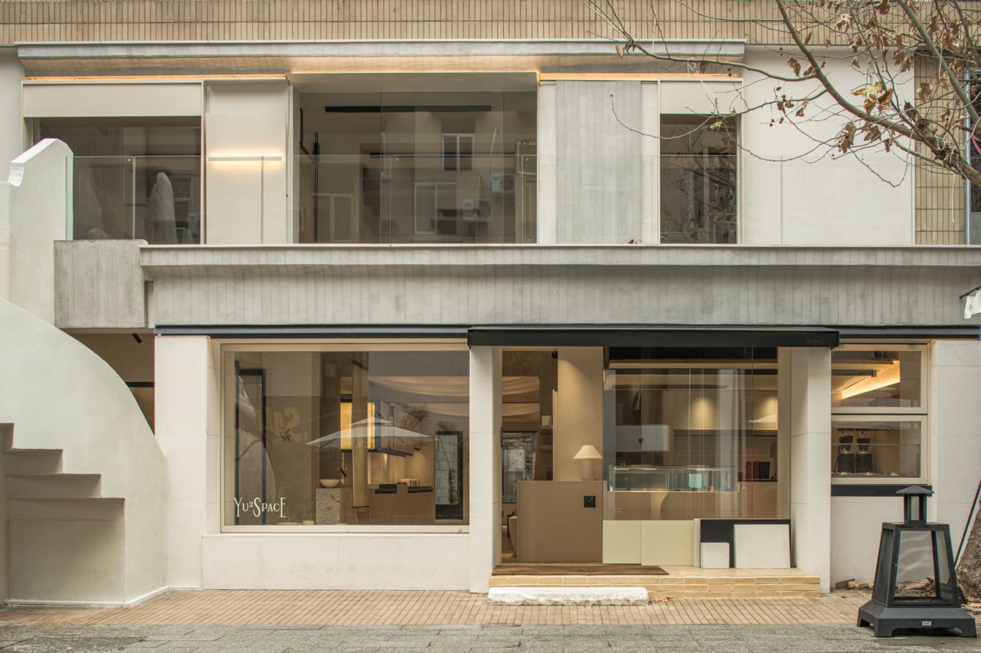 Modern storefront with a large window, black frame, and two chairs in a seating area