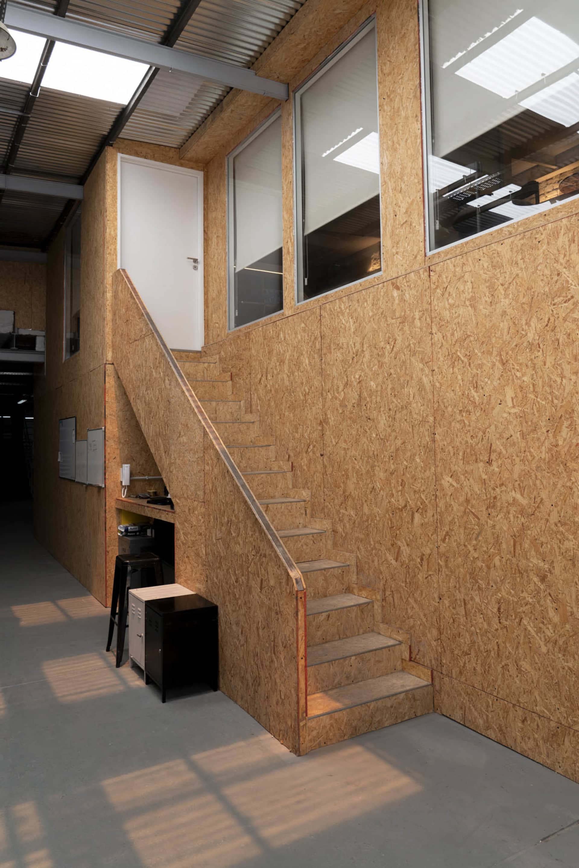 A wooden staircase in a building with a doorway and window, creating a warm and inviting atmosphere