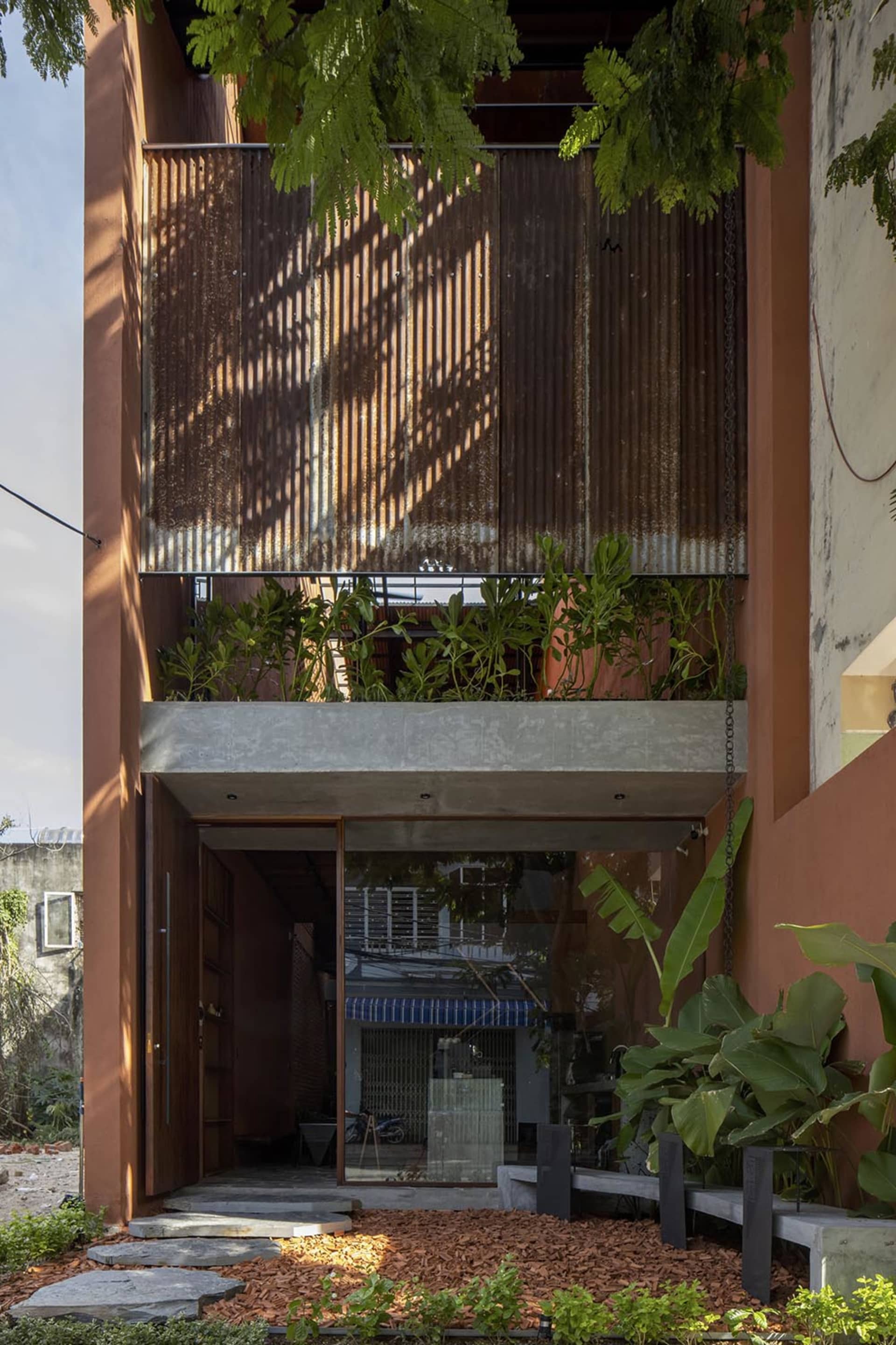 A colorful orange building with large windows and potted plants both inside and outside, creating a lively atmosphere