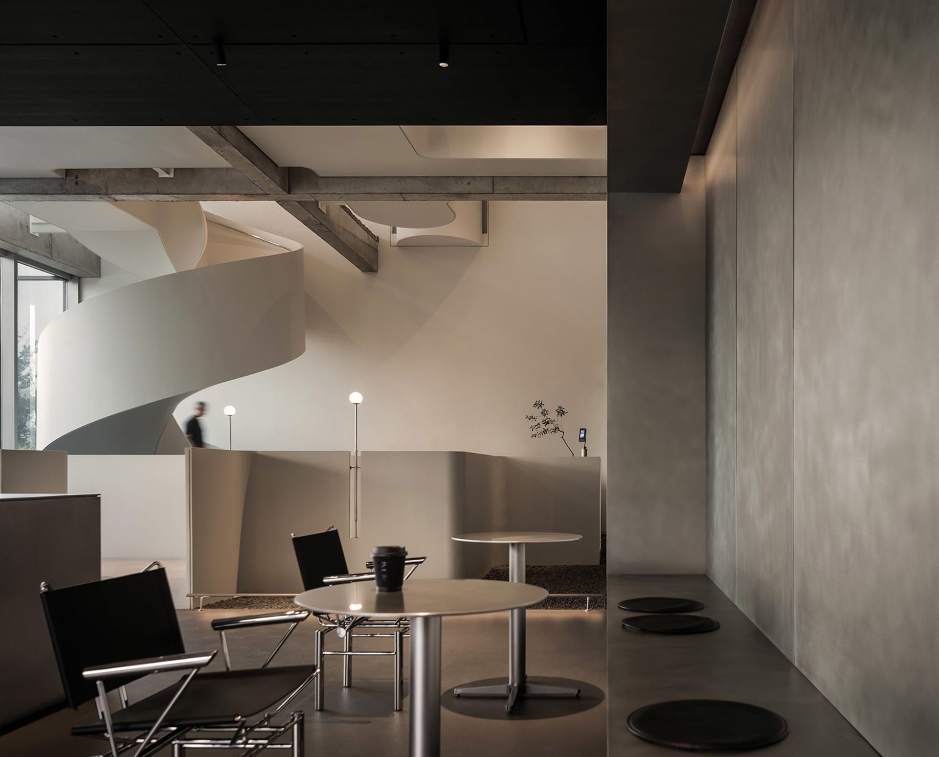 Modern lobby with a spiral staircase, chairs, and a dining table, set in a large open space