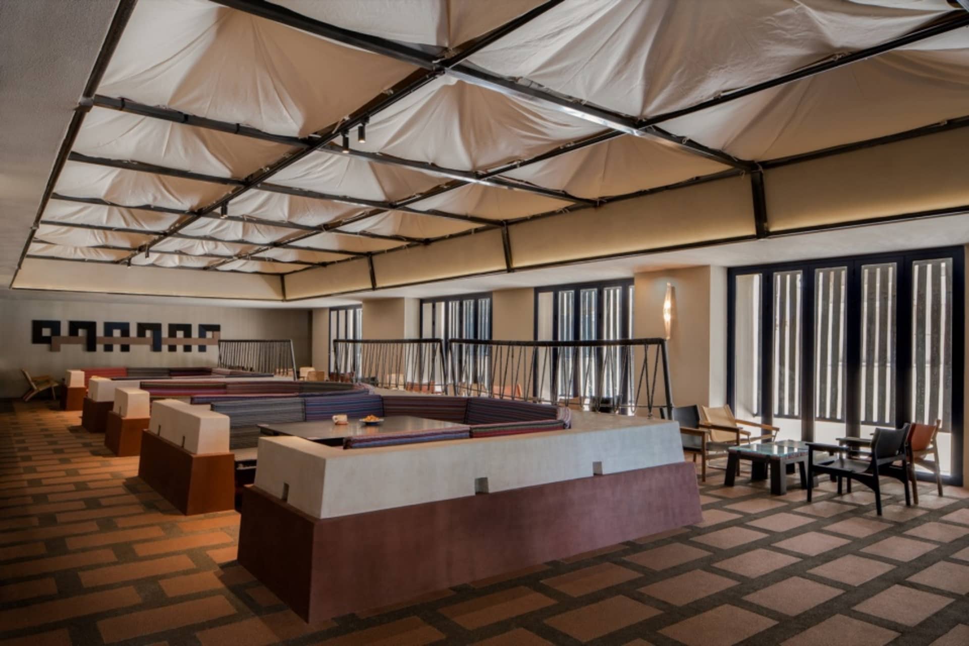 A large dining space with multiple tables and chairs, set up for a meal or event, with various items on the tables and a focus on functionality and comfort