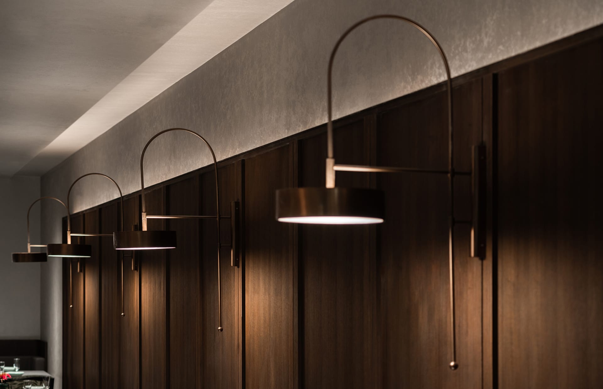 A dimly lit hallway with wooden walls and ceiling, lit by three pendant lights at varying heights