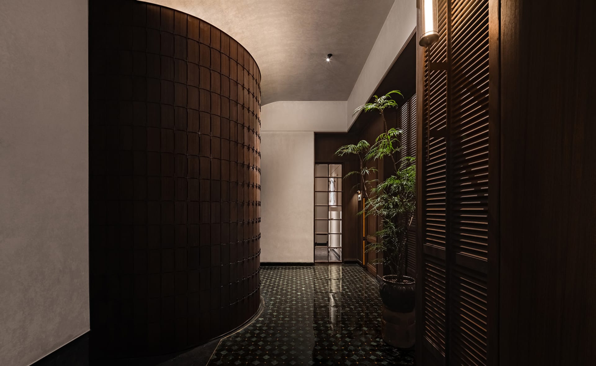 寧靜溫馨的走廊，配有黑白棋盤磚地板、兩盆盆栽與一張椅子