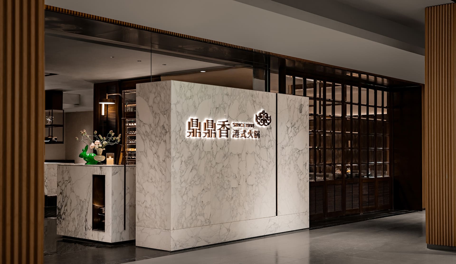 Modern restaurant interior with a marble wall, large window, and potted plants, featuring clean lines and minimalistic design elements