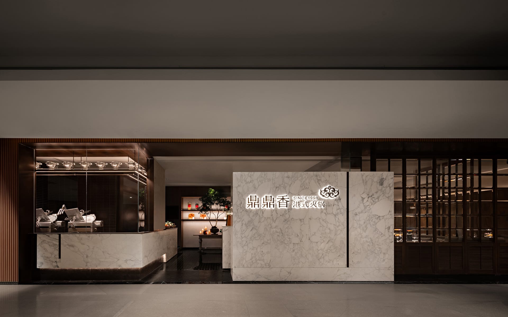 A modern Asian restaurant with a marble countertop, large window, and natural light, featuring potted plants, vases, and decorative elements