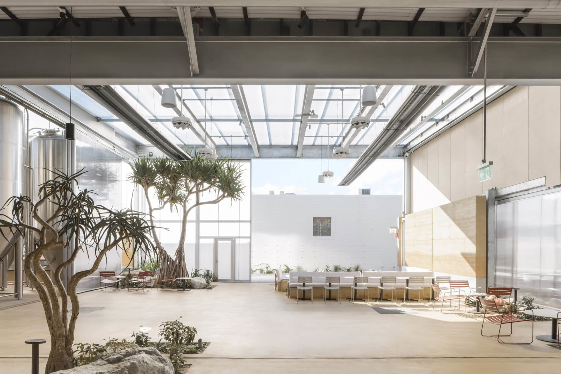 An open restaurant space with dining tables, chairs, and potted plants, creating a welcoming atmosphere