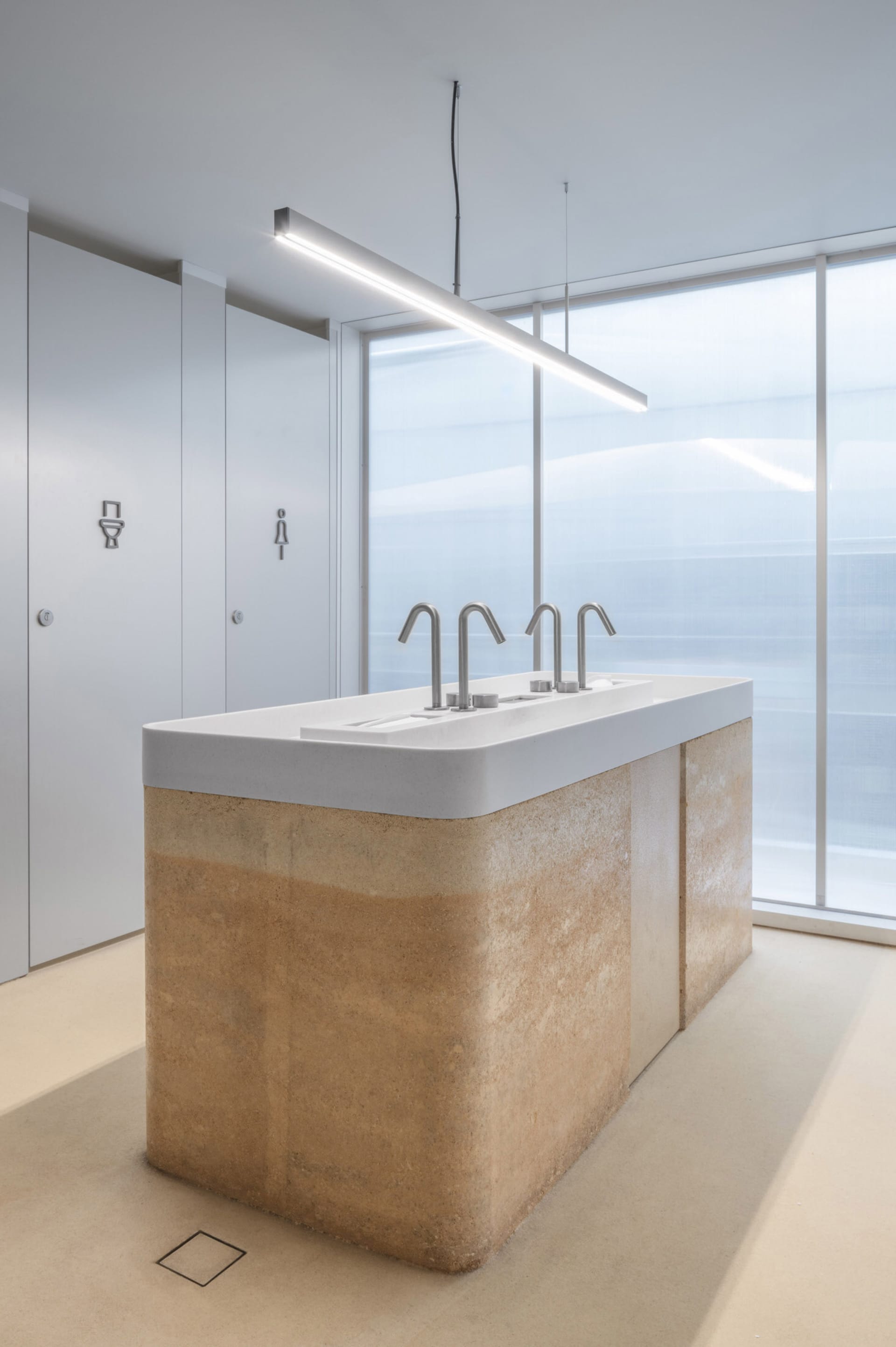A well-lit bathroom with three toilets and a sink, featuring a clean and functional space for personal hygiene and comfort