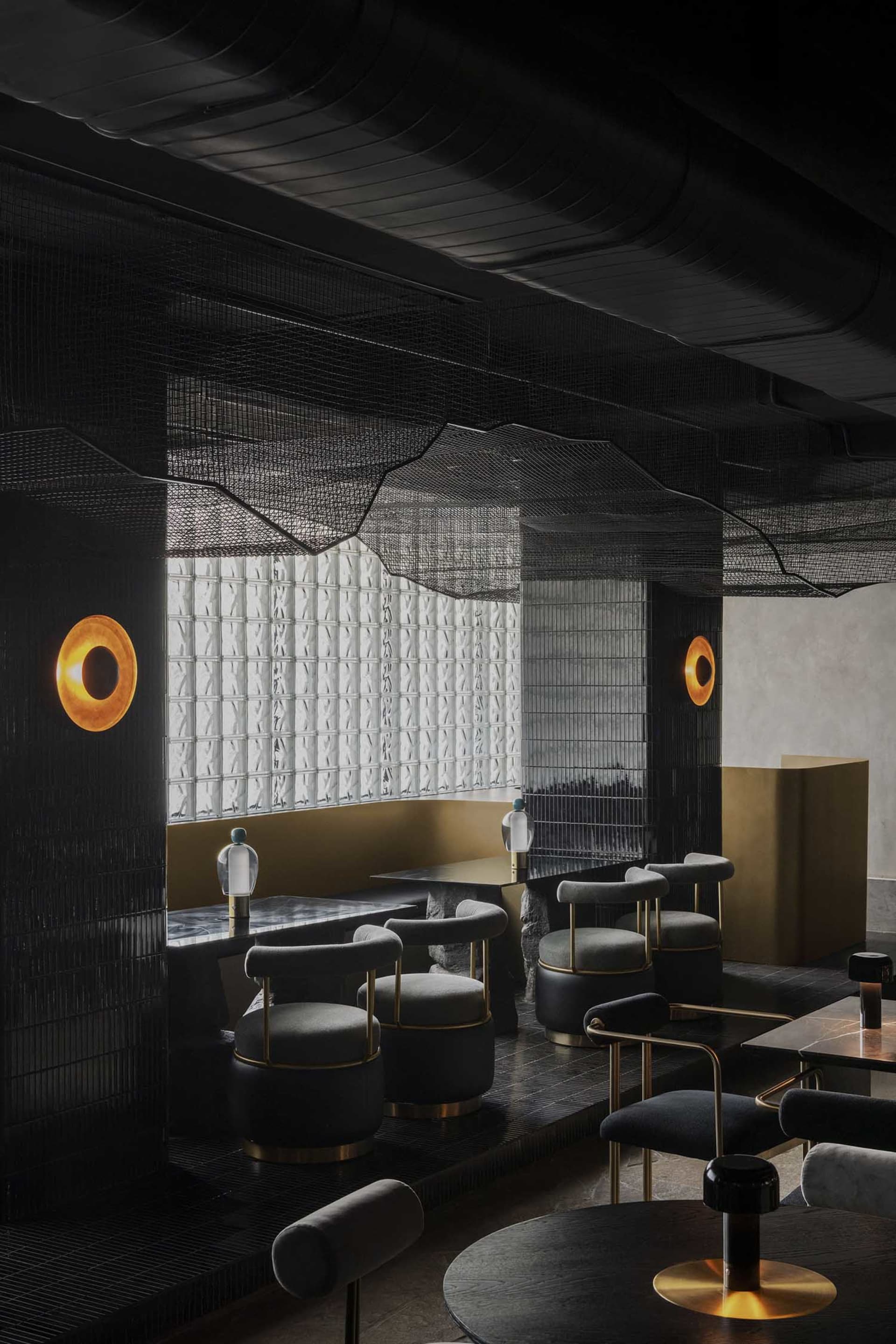 Modern restaurant interior with black and gold decorations, tables, chairs, and couches in a spacious dining area