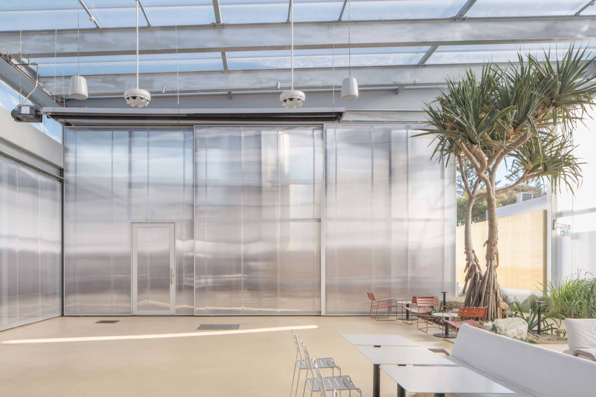 a contemporary living space with a glass wall, metal frame, chairs, and a dining table