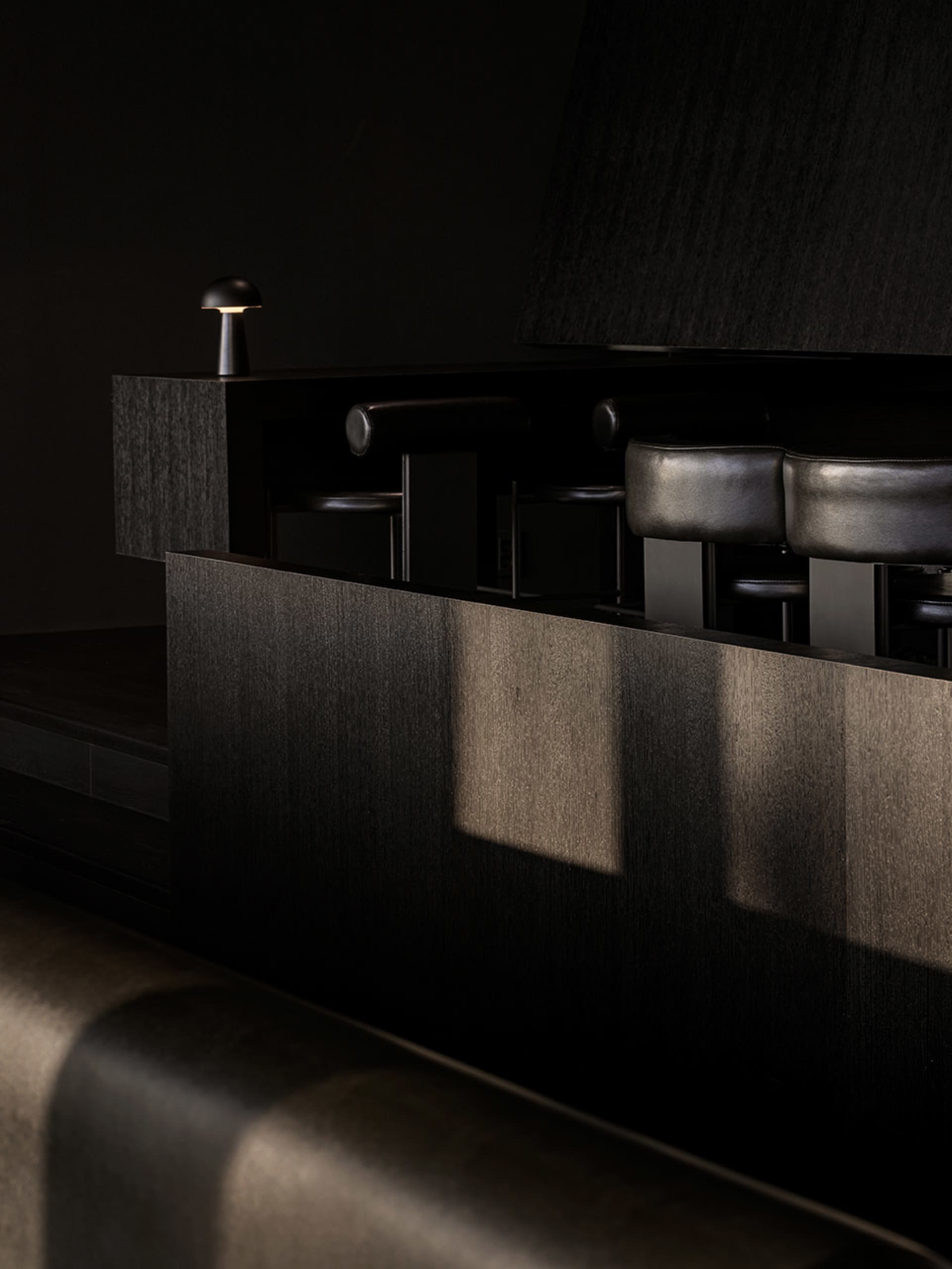 Dark bar area with black leather chairs and couches, intimate and cozy atmosphere