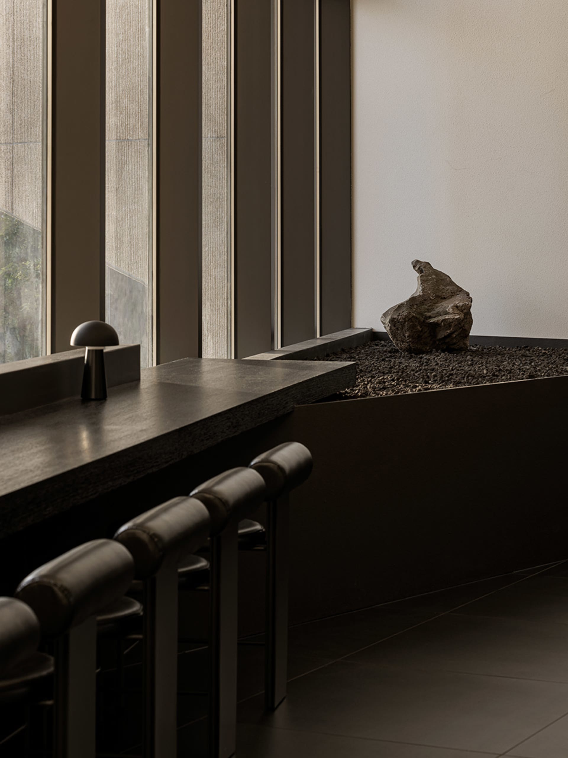 A minimalist kitchen with a countertop, a rock on display, and two chairs near a window