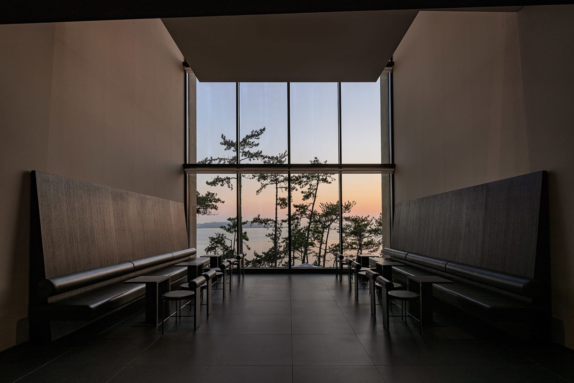寧靜水岸建築，擁有眾多窗戶、長椅與夕陽景觀