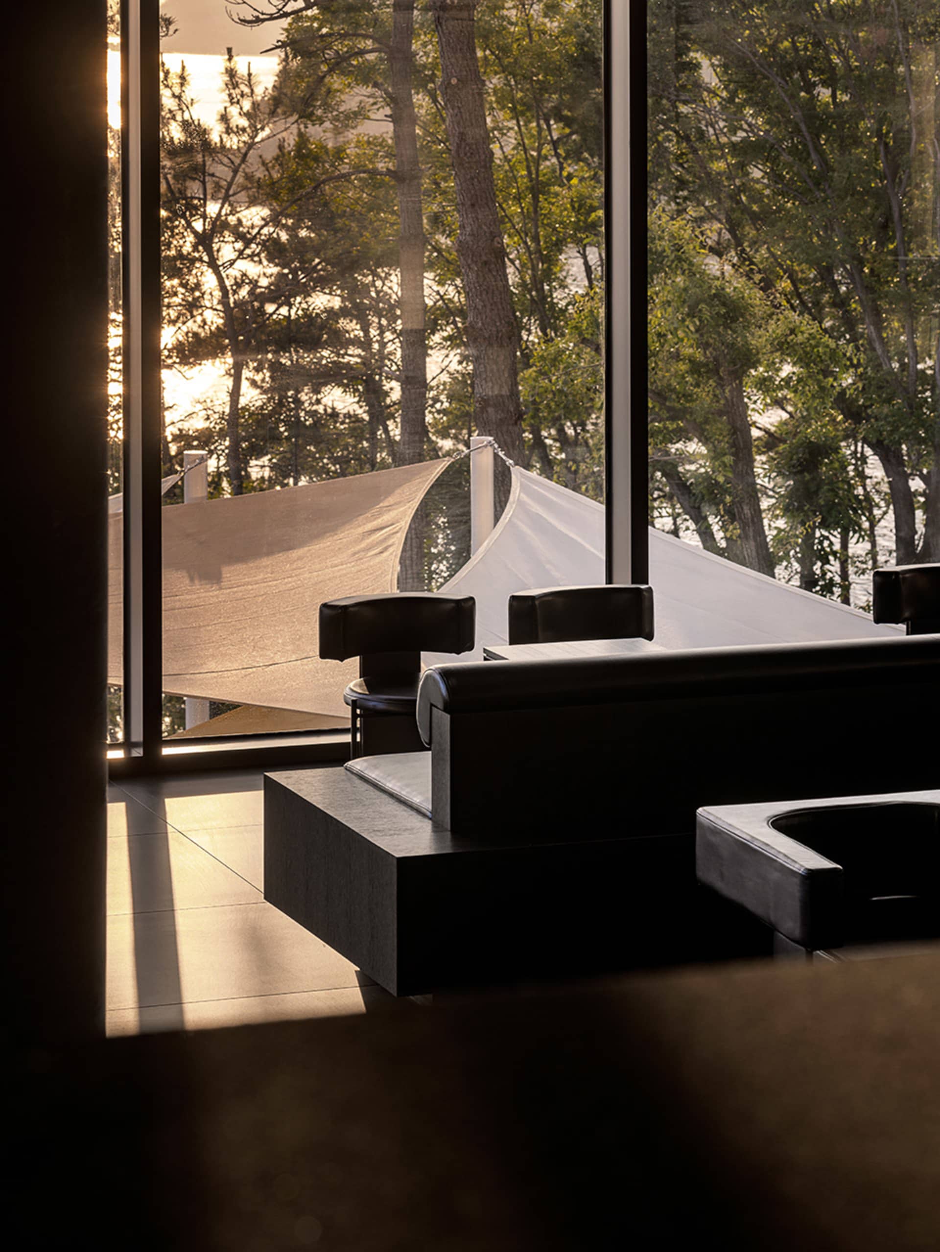 A well-lit living space with a large black chair in front of a window, accompanied by a smaller chair, creating a comfortable and inviting atmosphere