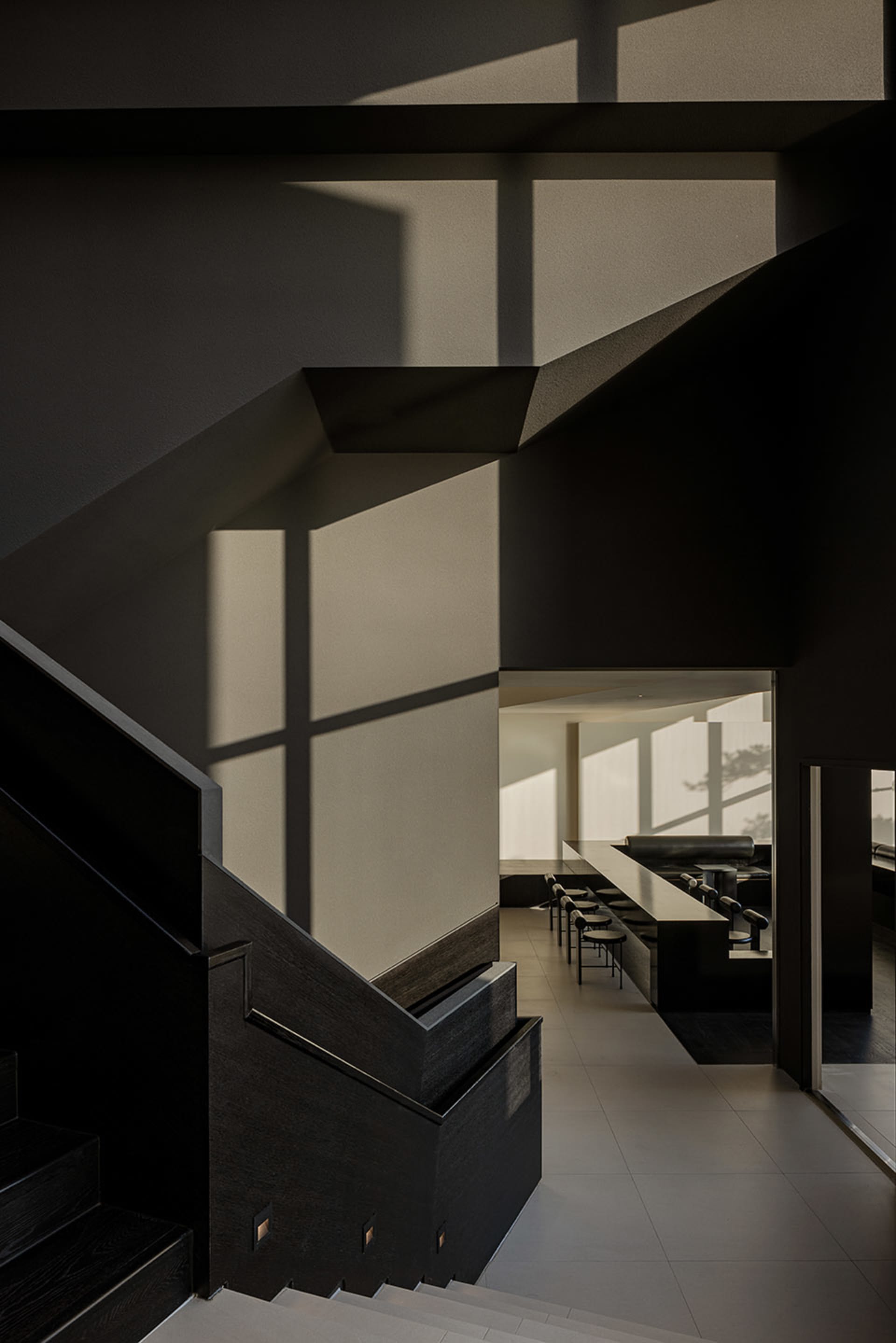Dark interior space with a black staircase, chairs, and industrial-style decor