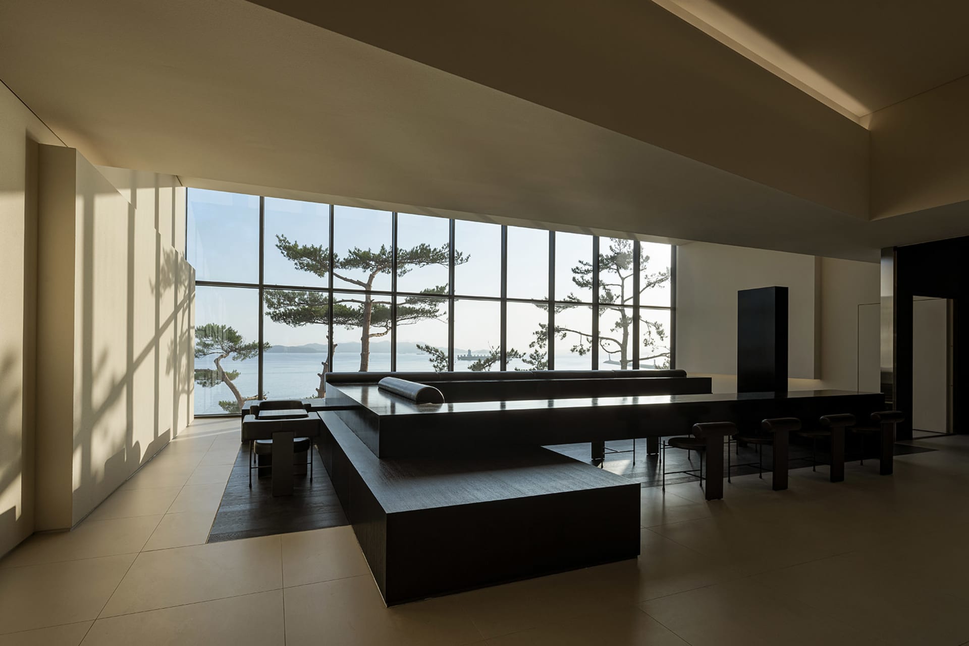 Open modern living space with black countertops, a black table, and natural light from a large window with a view of trees outside