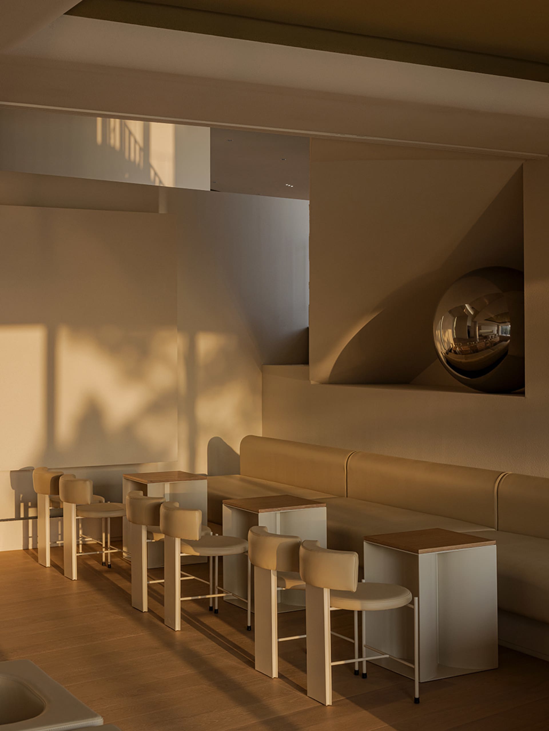 A well-lit living area with a couch, chairs, tables, and a large mirror, featuring a combination of white and brown elements, with a warm and inviting atmosphere