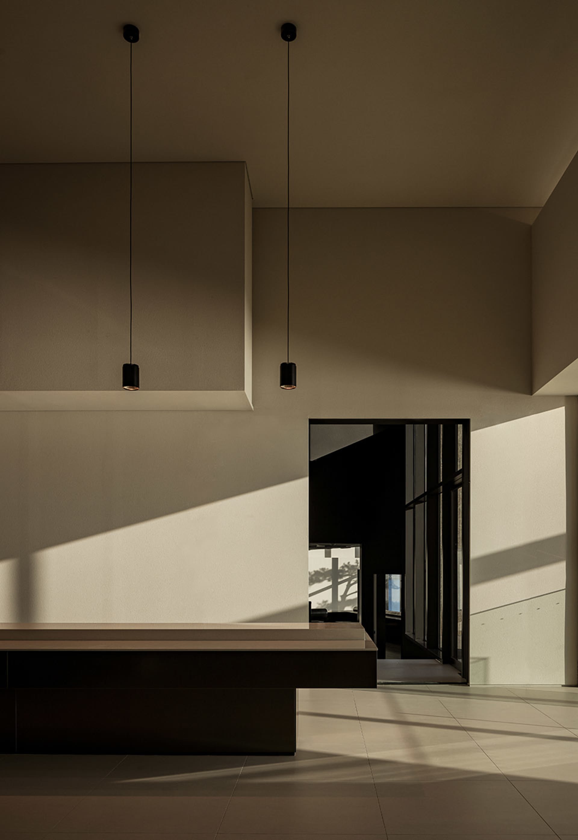 A modern dining space with a concrete wall, a dining table, chairs, and a couch, lit by natural light from a window