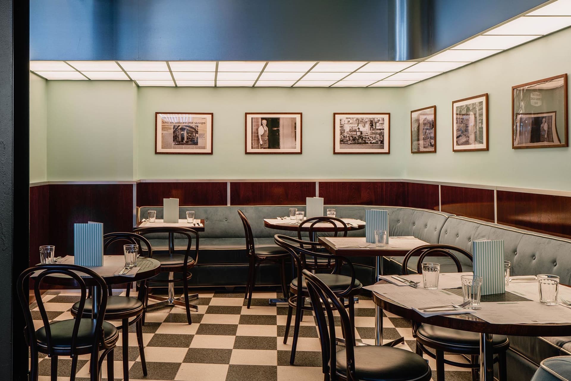 An empty restaurant with tables, chairs, and hanging pictures creating an inviting atmosphere