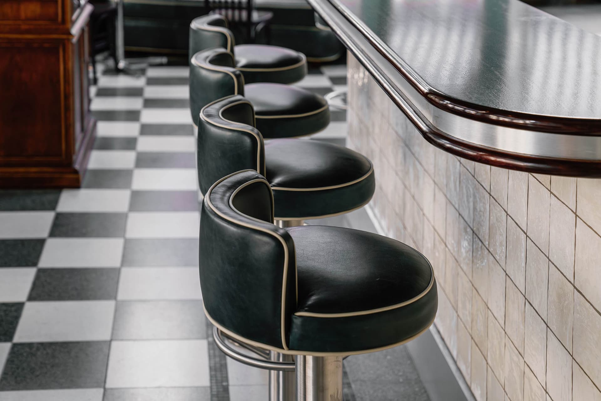 A modern bar with multiple black leather stools and a well-lit counter, creating an inviting atmosphere for customers